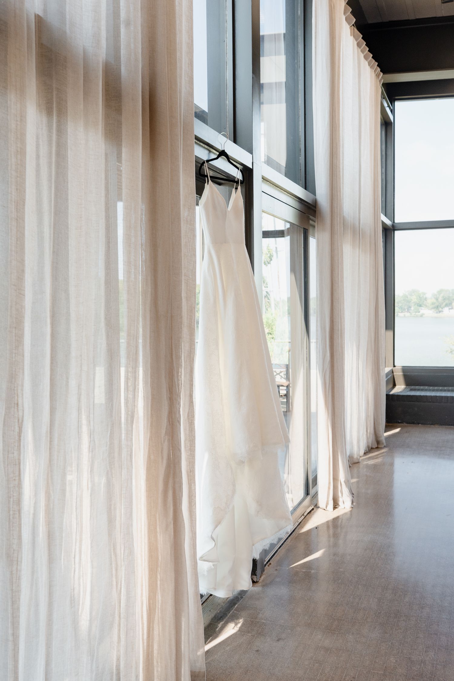 Long hallway with white curtains and natural light streaming through windows along one side.