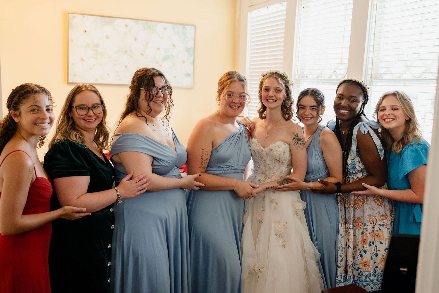 Group of women in light blue dresses standing together in a sunlit room.