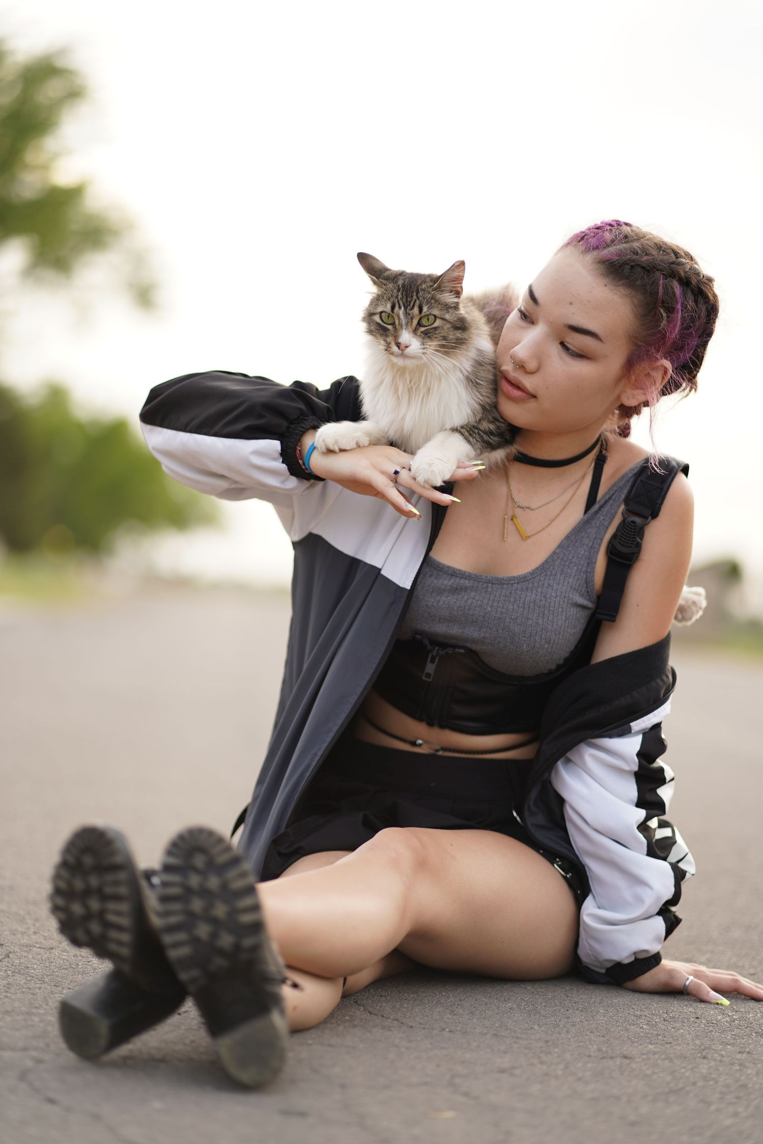 A grey and white cat lounges in someone's lap while wearing black and white athletic wear.