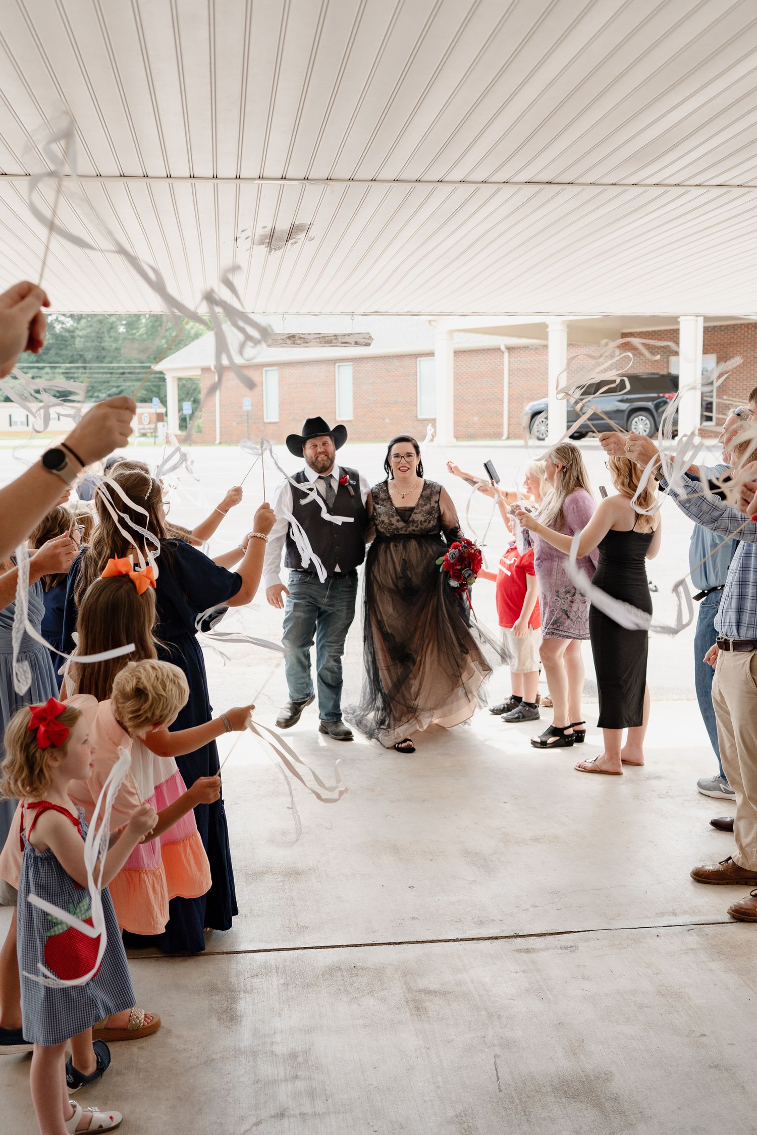Wedding guests dance together under a covered outdoor area during a lively reception celebration.