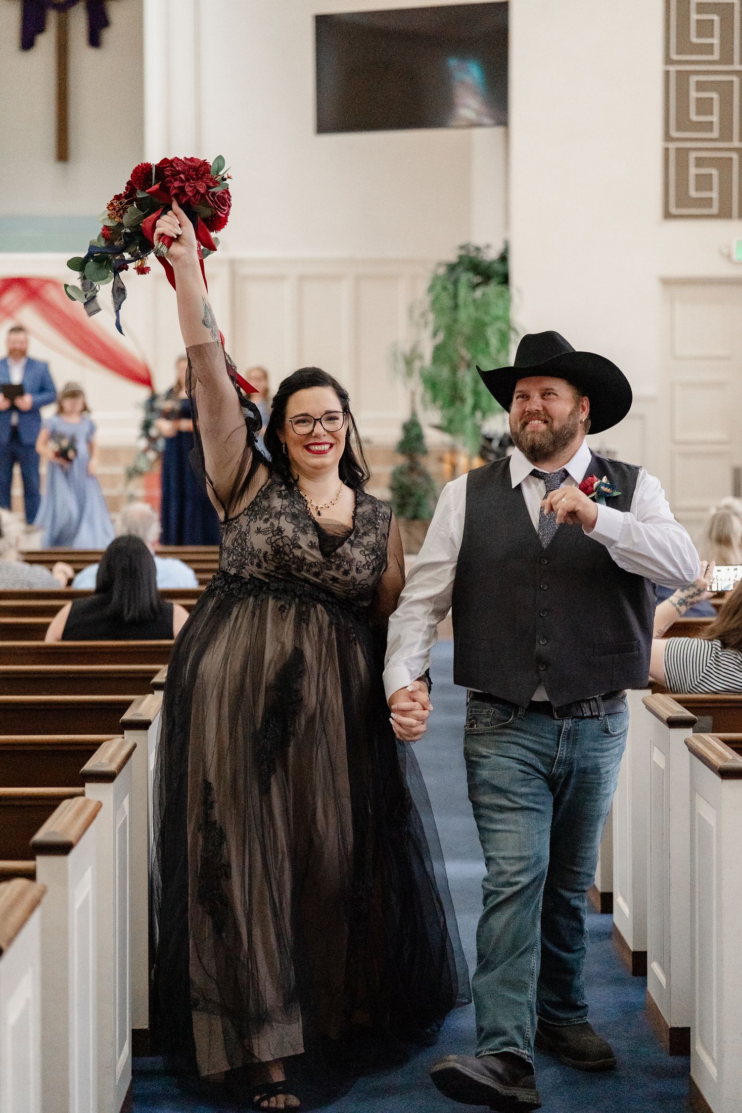 Joyful celebration inside a church with wedding party members raising their arms.