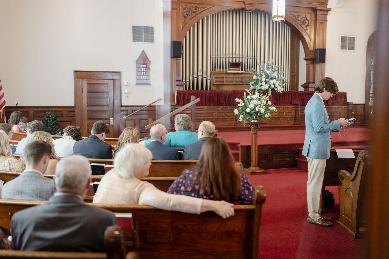 Interior view of a traditional church sanctuary with wooden pews and organ pipes during a service.