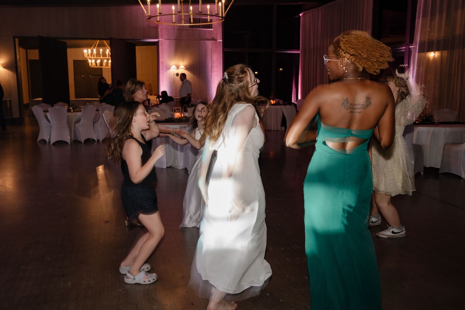Wedding reception dance floor with guests celebrating under dimmed lighting.