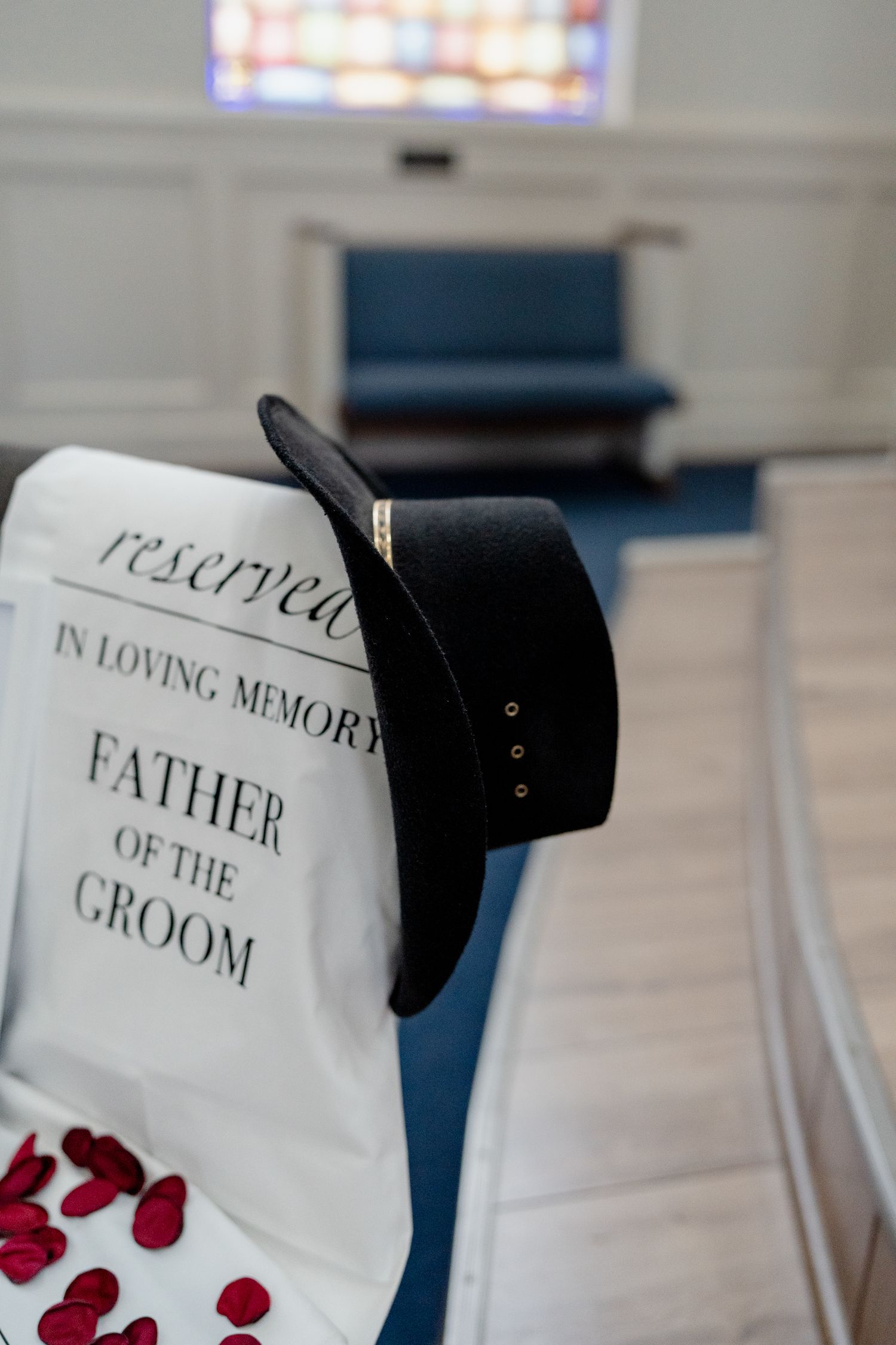 Memorial sign with rose petals scattered on a church pew.