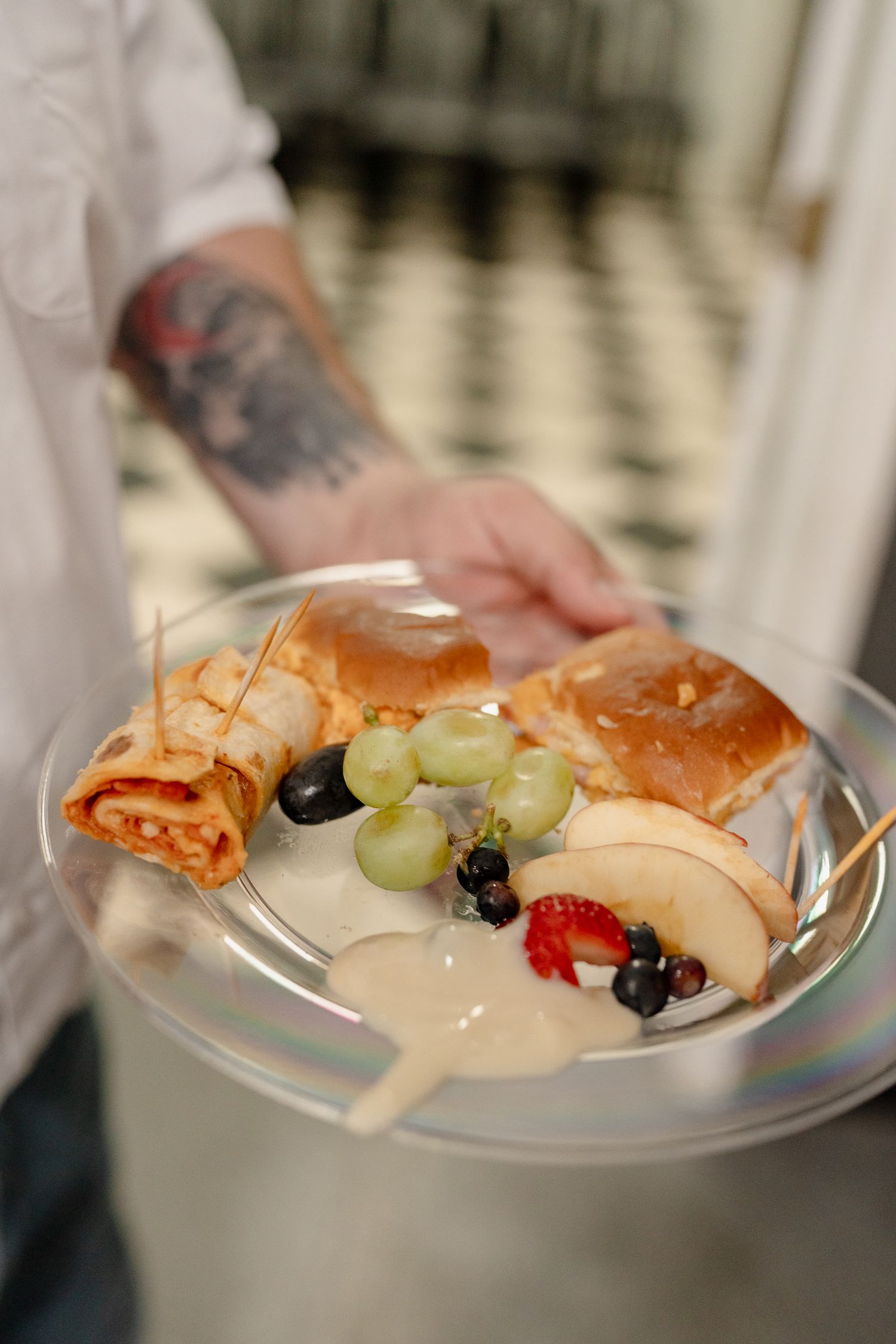 A plate of fresh fruit and appetizers including shrimp, grapes, and cheese arranged on a white serving dish.