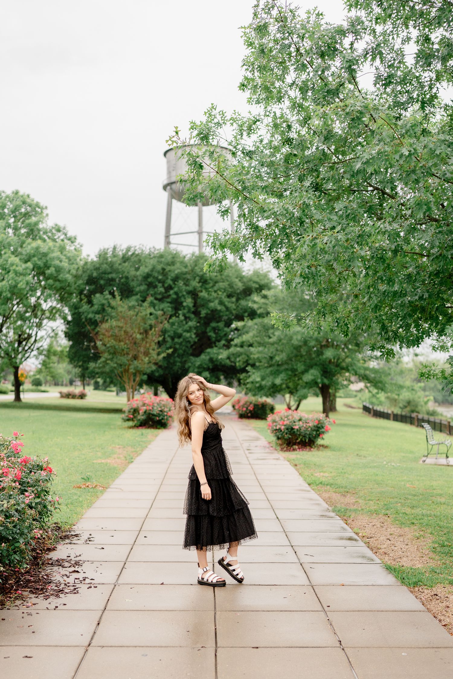 Outdoor fashion shoot on concrete pathway surrounded by green landscaping.