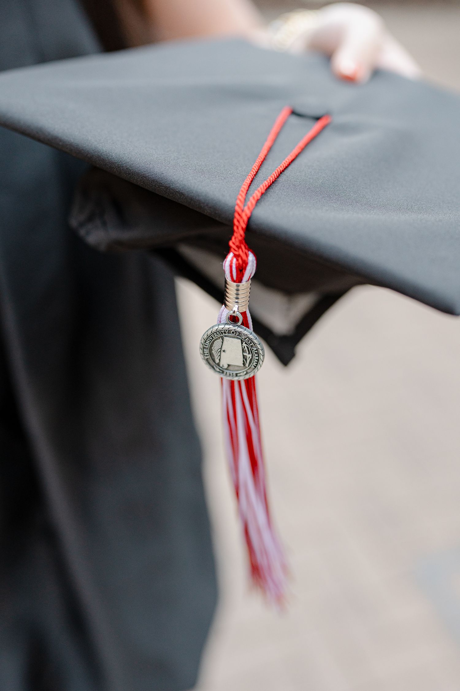 Close-up view of graduation cap tassel with red and white stripes against a dark background.
