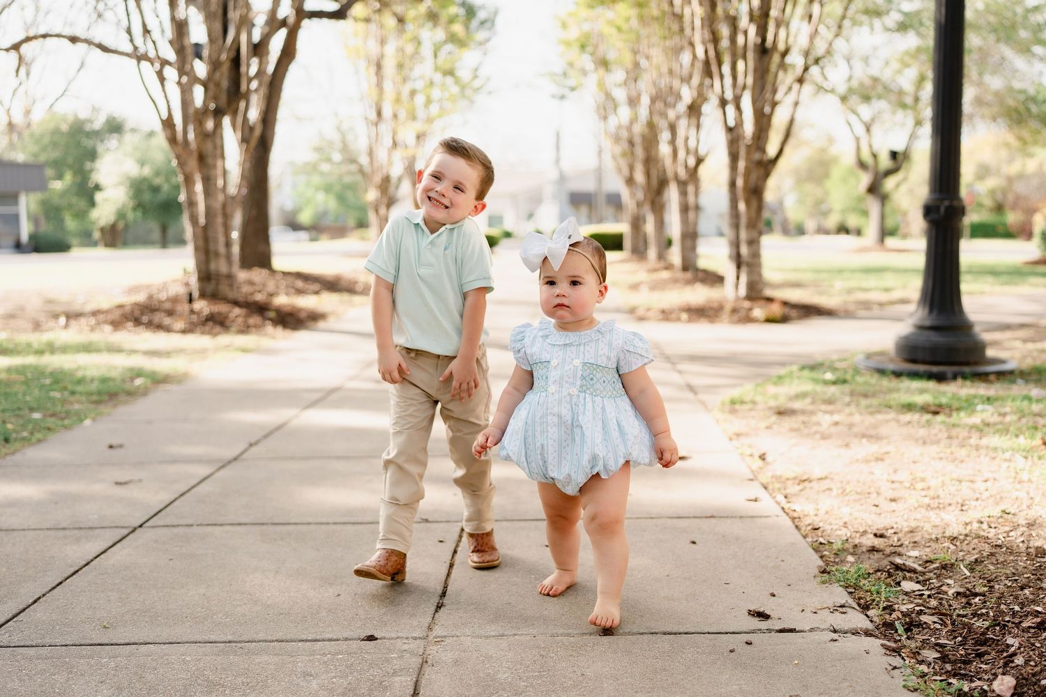 Two children walking together on a tree-lined pathway in coordinating outfits.