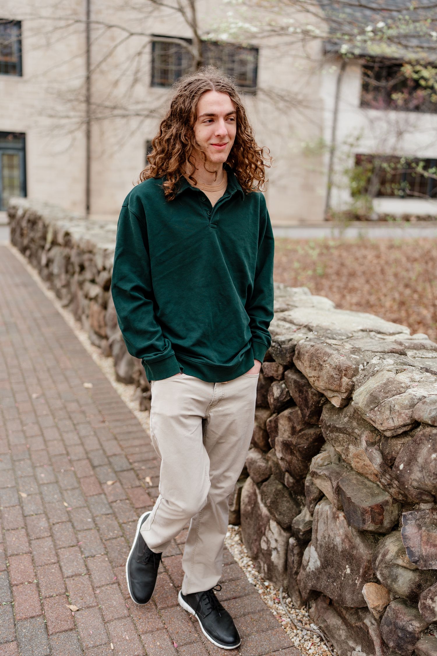 Walking shots along a brick pathway and stone wall wearing a green hoodie and khaki pants.