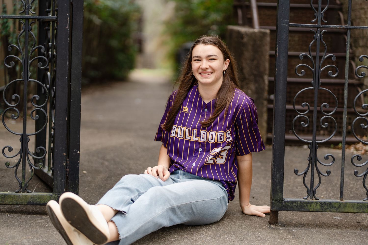 Outdoor portrait session against decorative iron gates and greenery.