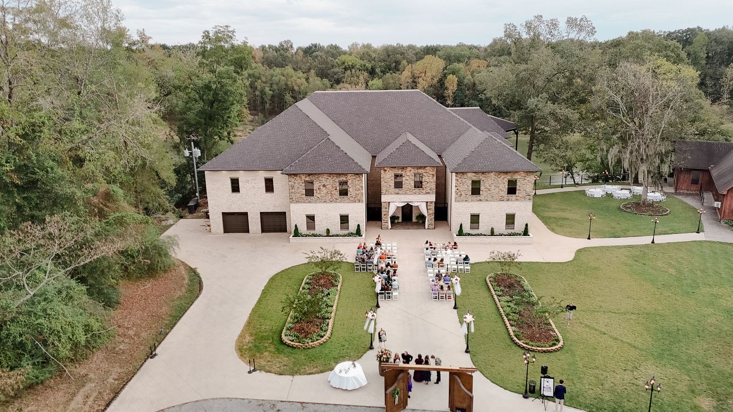 Aerial panoramic view of a large ranch-style home with multiple garages and well-maintained landscaping on spacious grounds.