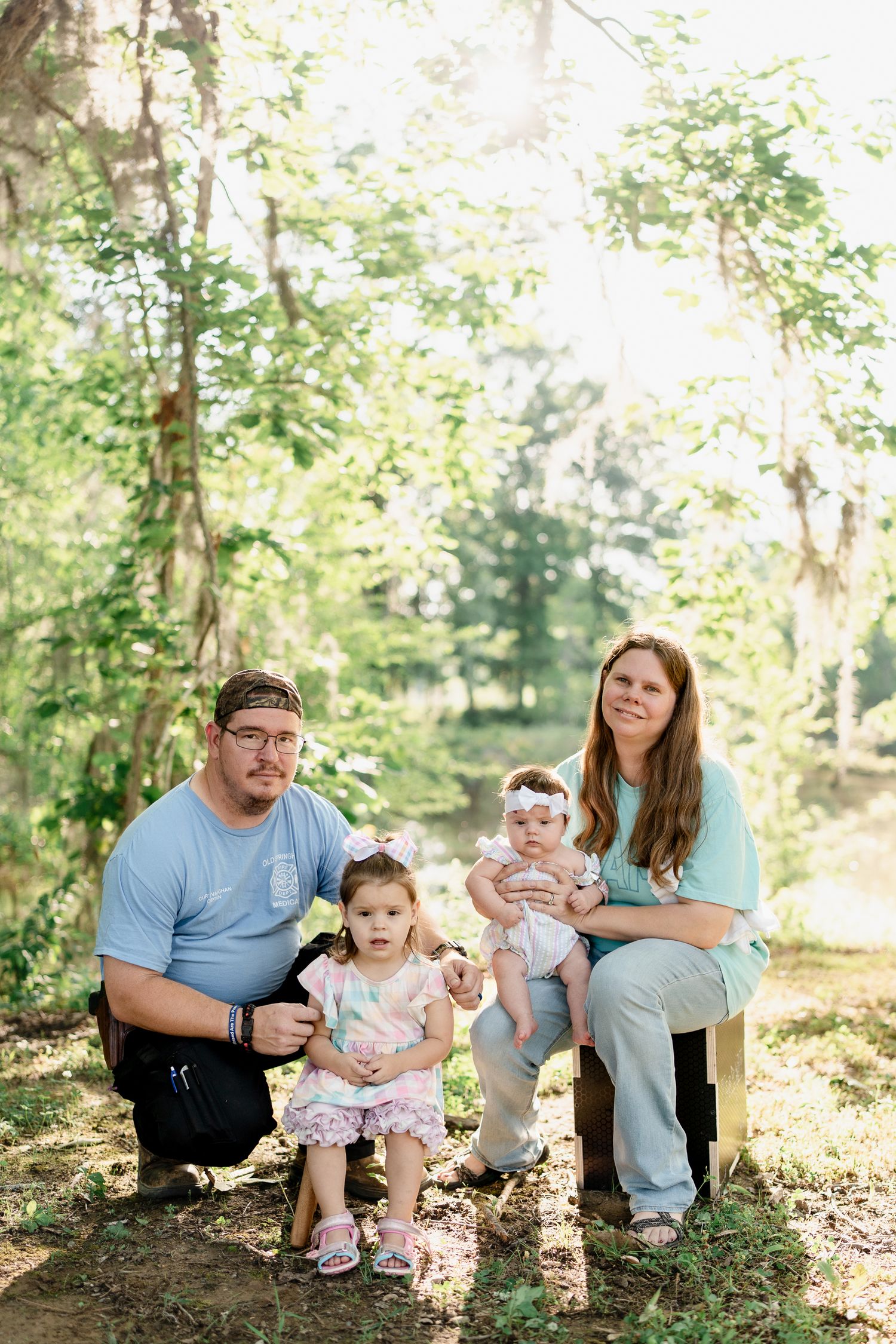 Candid family photos taken on a forest floor with dappled sunlight filtering through the trees.