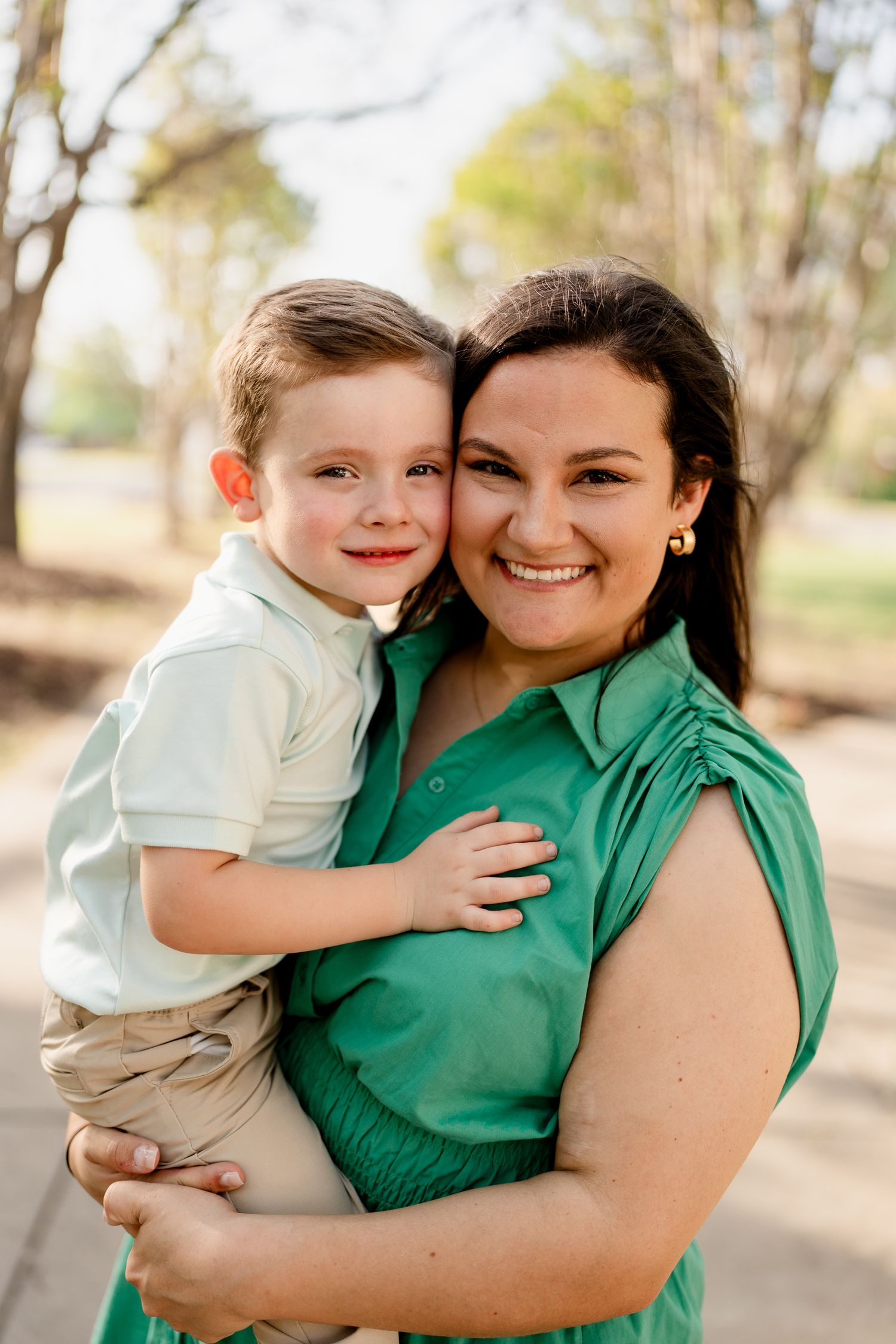 A heartwarming moment between a woman in green and a child captured in natural outdoor lighting.