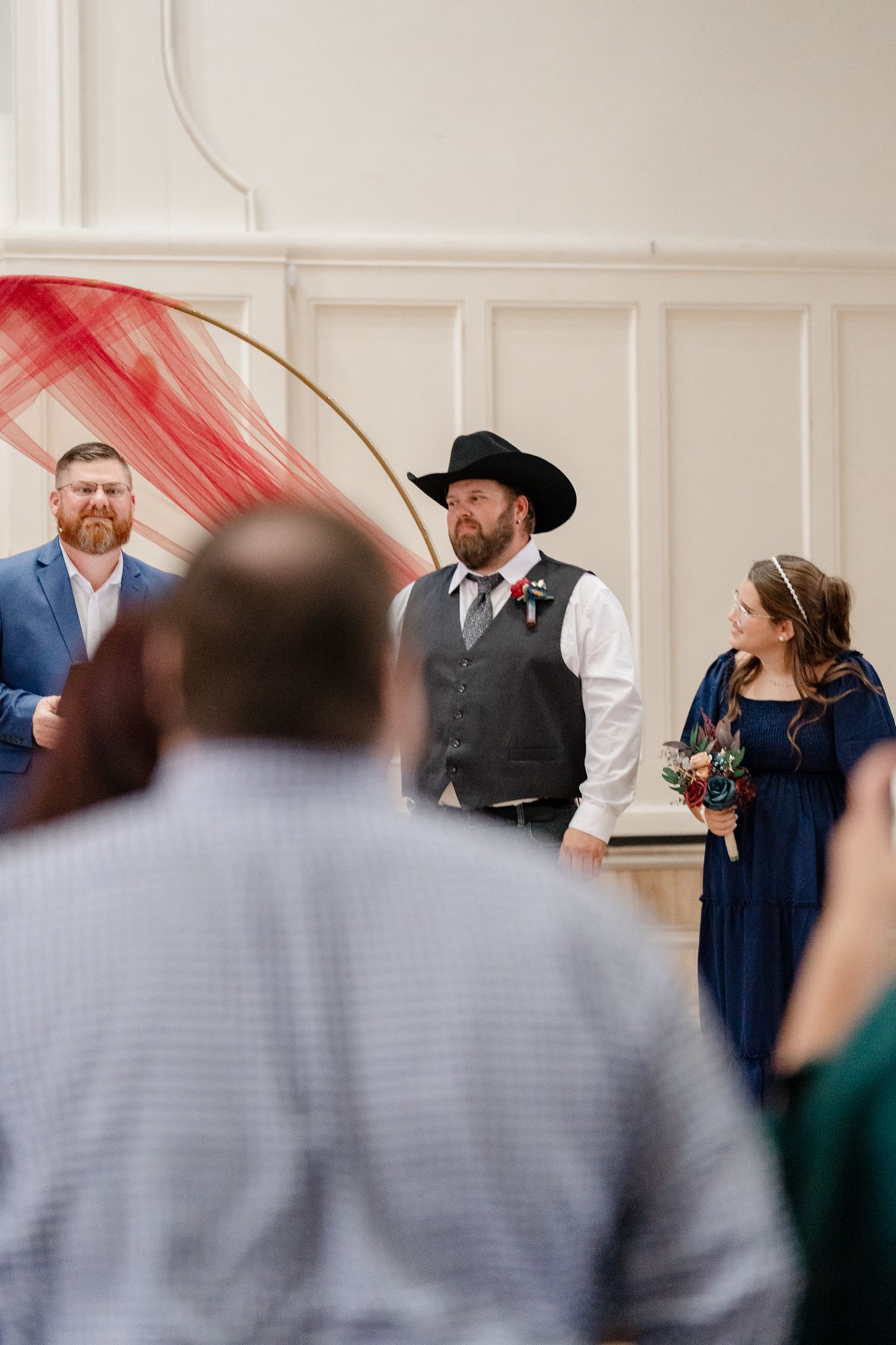Wedding party members in navy blue and gray attire gather for indoor celebration photos.