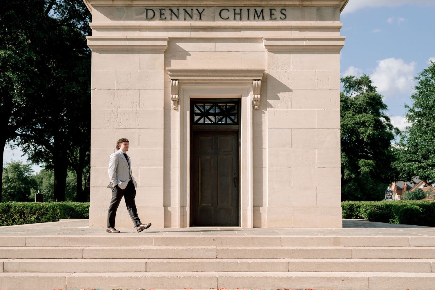 A person walks past the Denny Chimes monument at the University of Alabama on a sunny day.