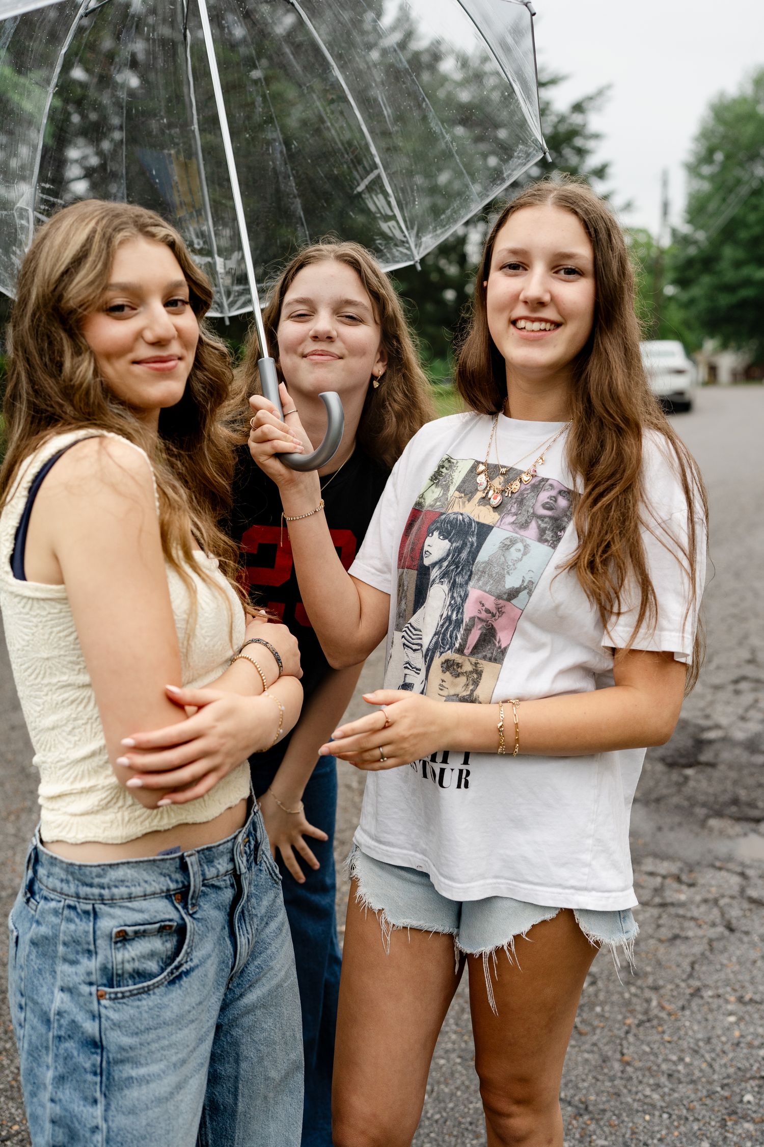 Friends having fun with a clear umbrella on a cloudy day outdoors.