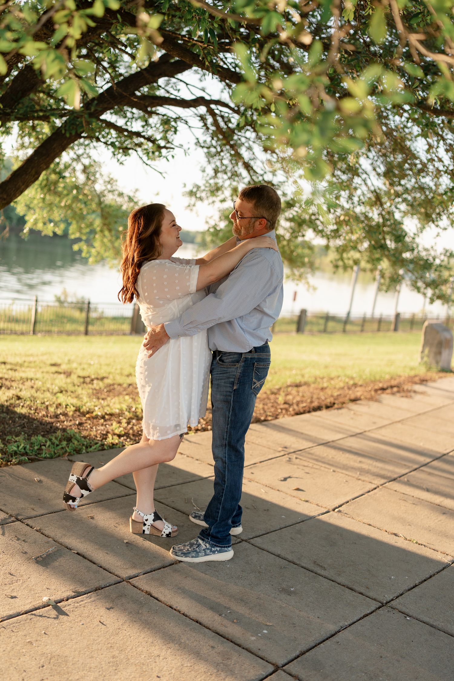 Couple sharing intimate dance moves on a paved pathway during sunset.