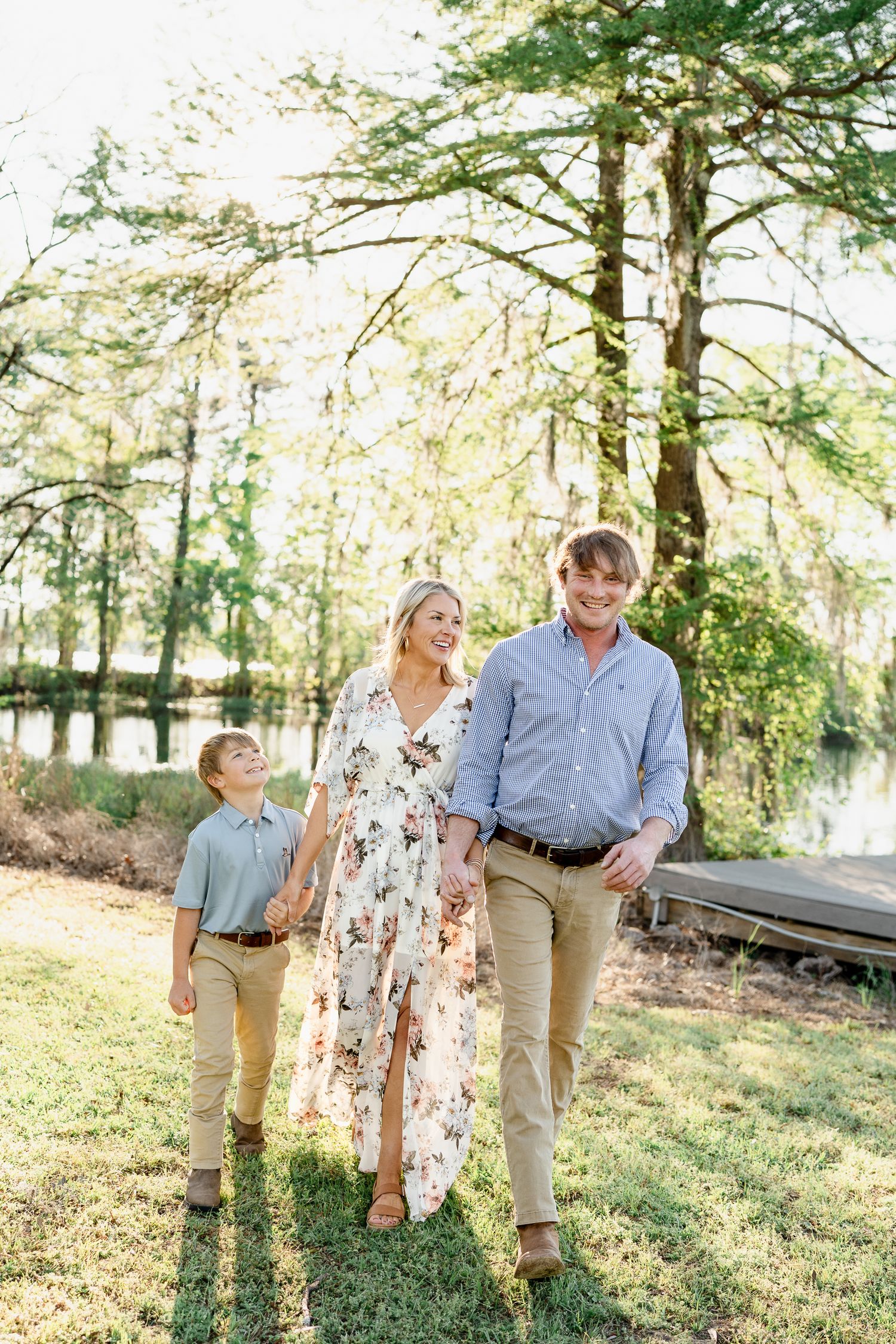 Family walks together through wooded area during golden hour photo session.