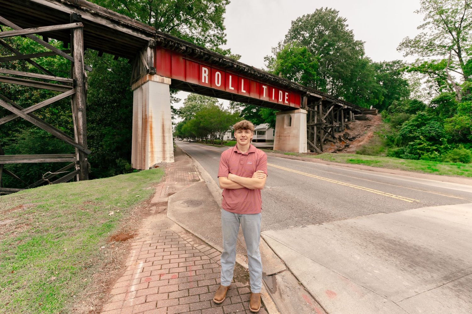 View of a brick pathway leading to a bridge with 'Roll Tide' text overhead.