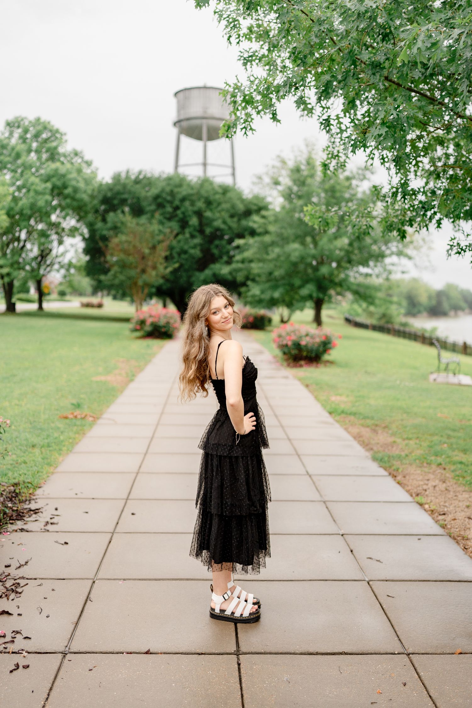 Fashion portrait series on concrete path with landscaped grounds and trees.