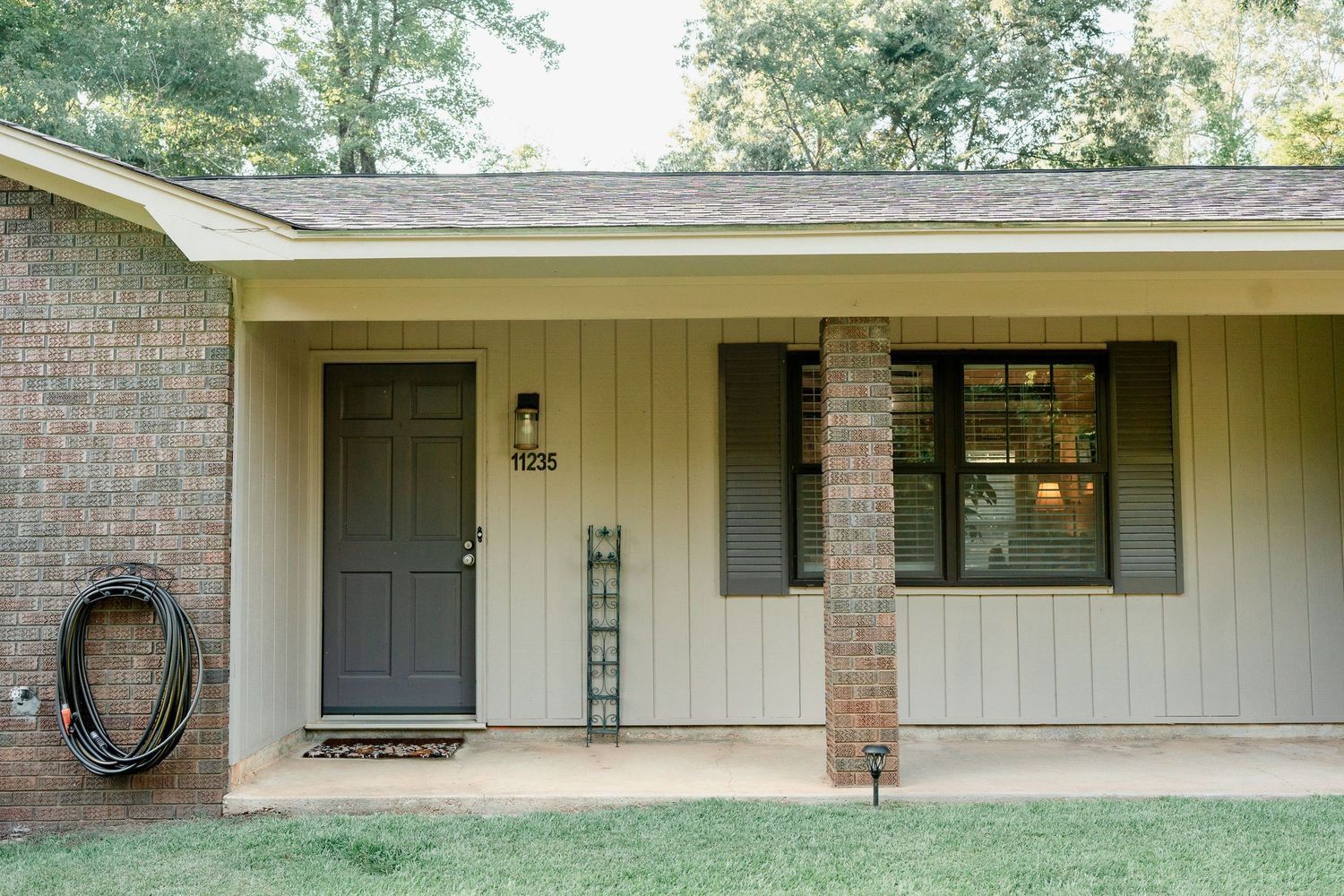 Modern ranch home exterior with brick and siding features a gray front door and covered porch entrance.