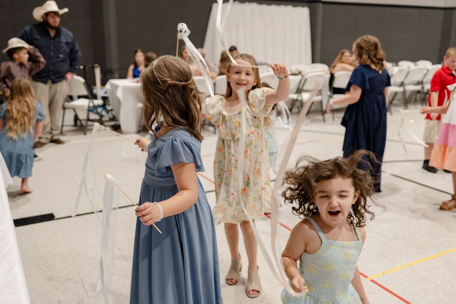 Children dance and play together at an indoor party or event with decorations and streamers.