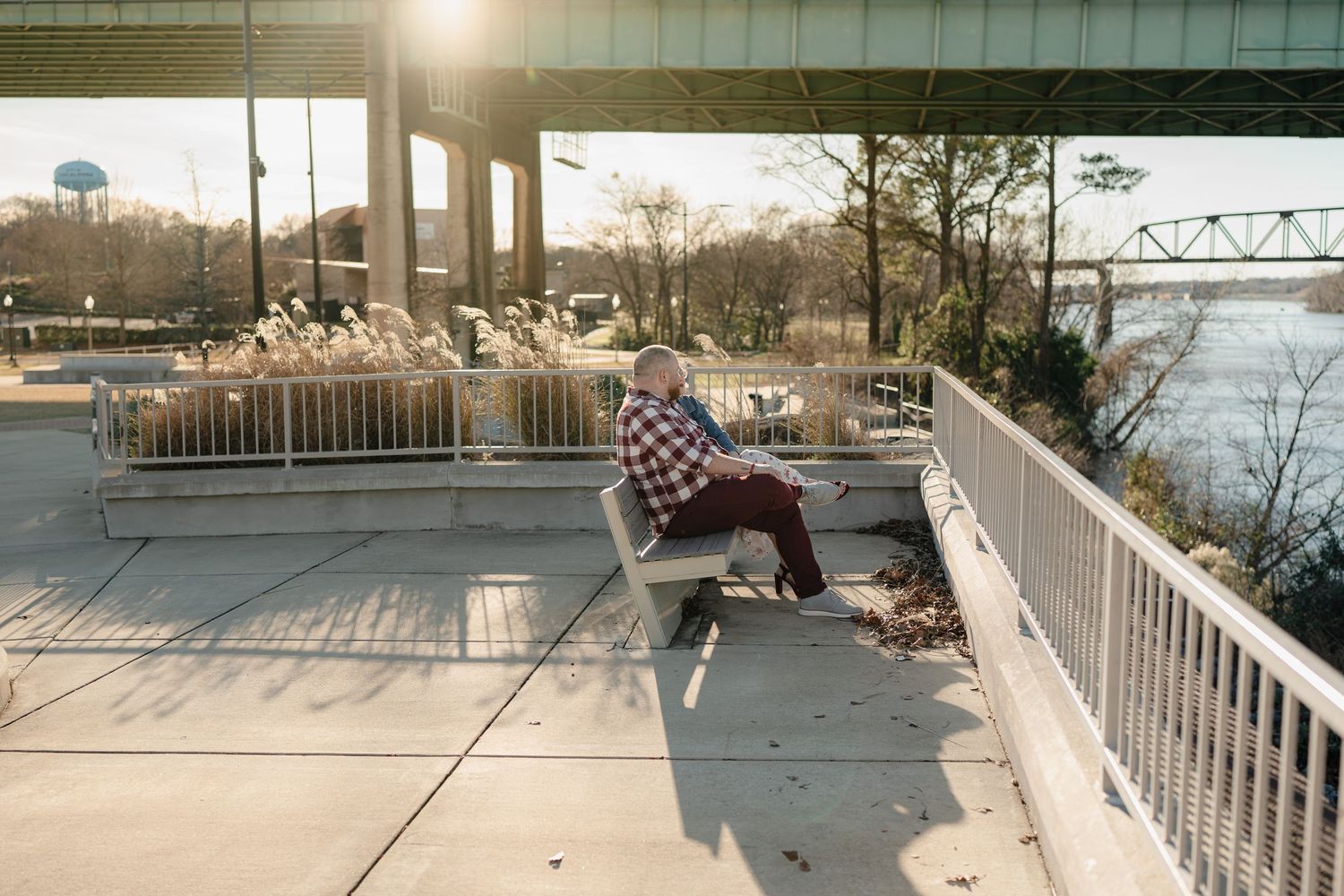 Skateboarder performs a sequence of tricks on a concrete ledge at a waterfront skate spot during sunset.