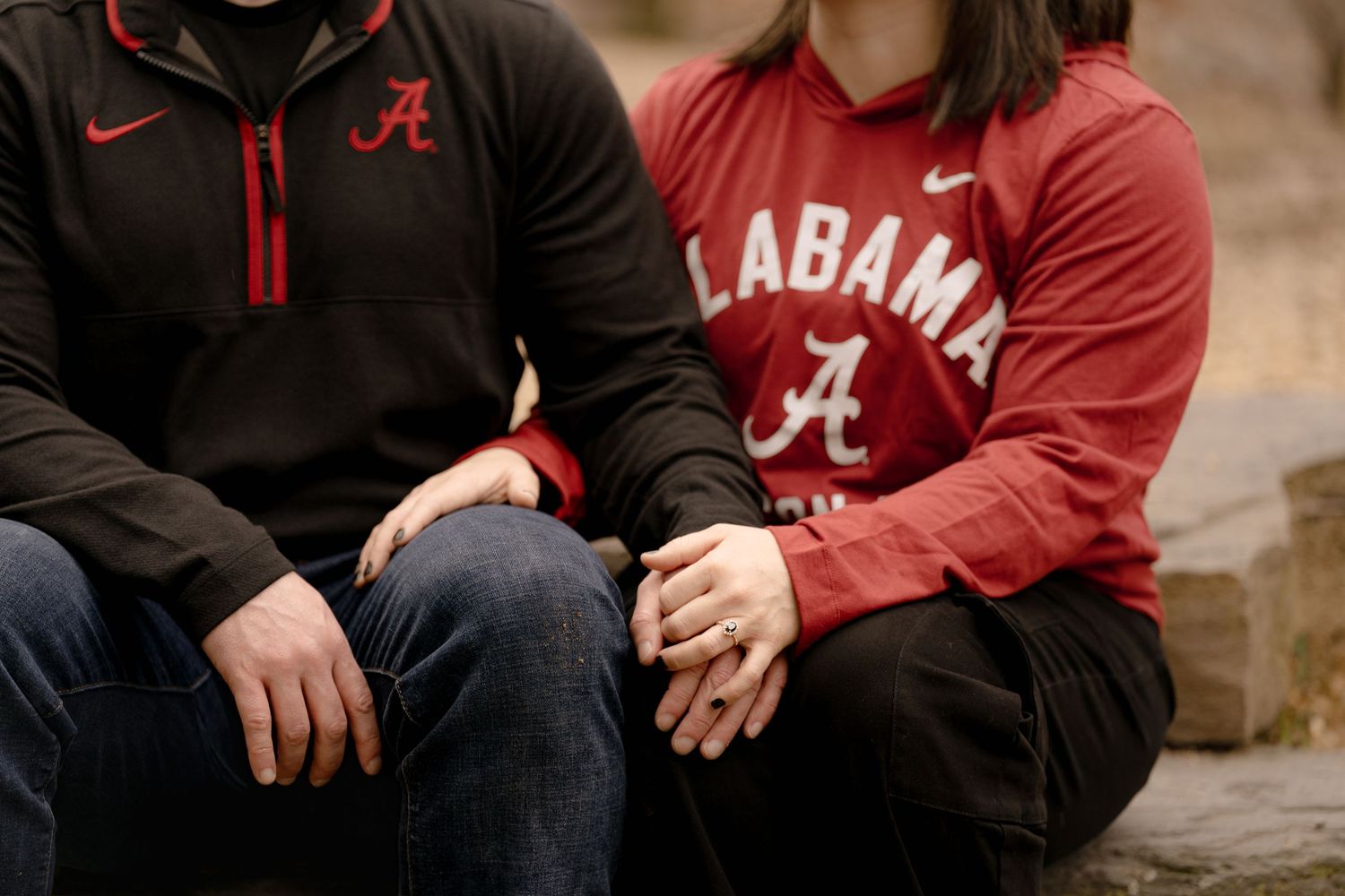 Multiple people wearing Alabama Crimson Tide apparel sitting together on bleachers or steps.