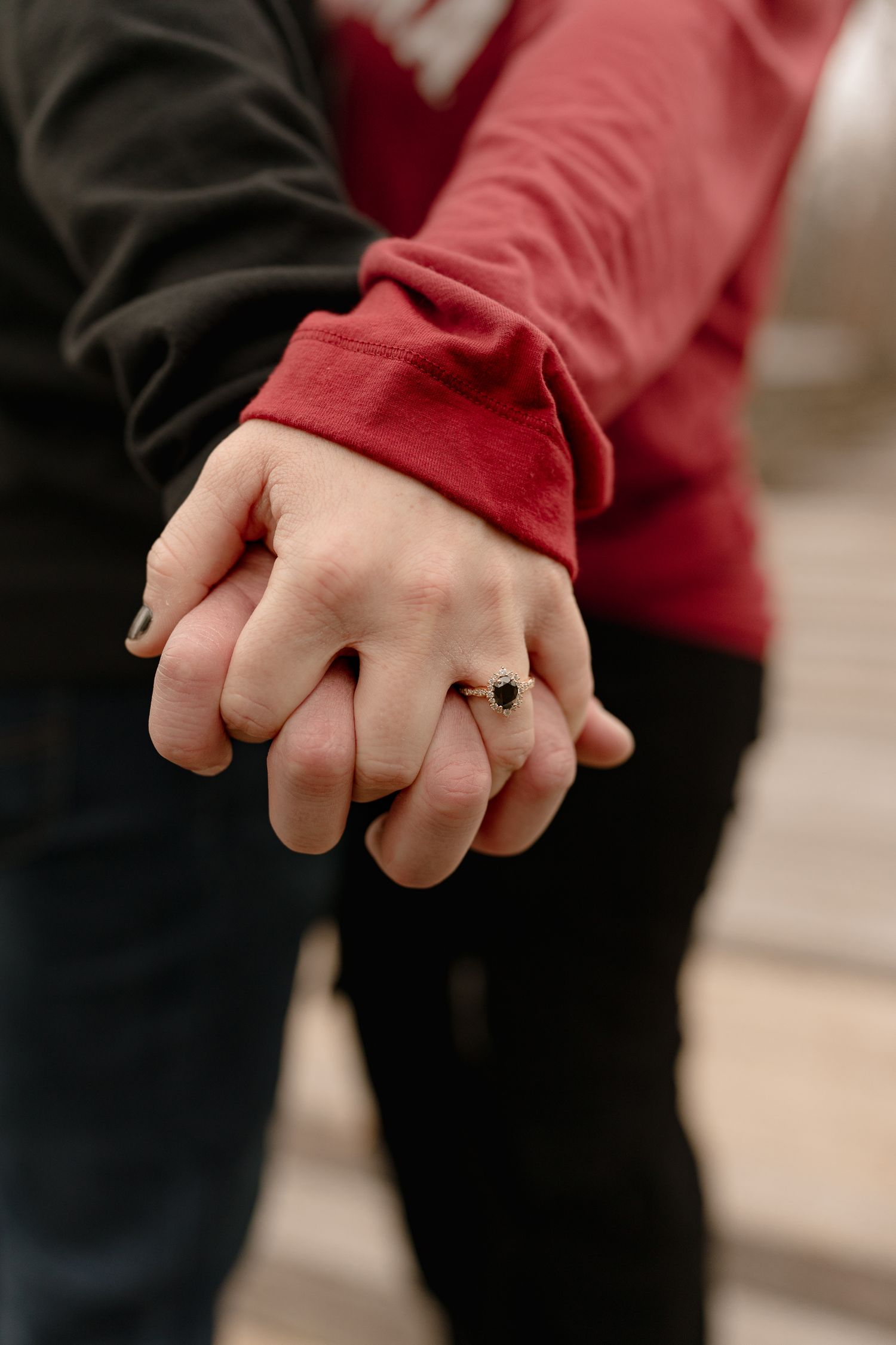 Close-up view of hands wearing a red sleeve and black clothing with a ring visible.