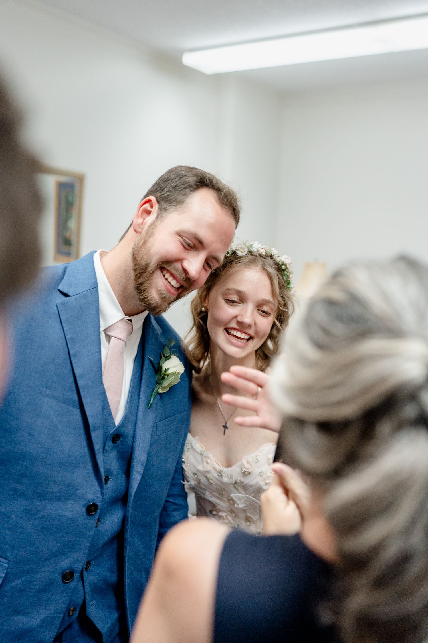 A couple shares a joyful moment together at a wedding celebration, dressed in formal blue suit and elegant attire.
