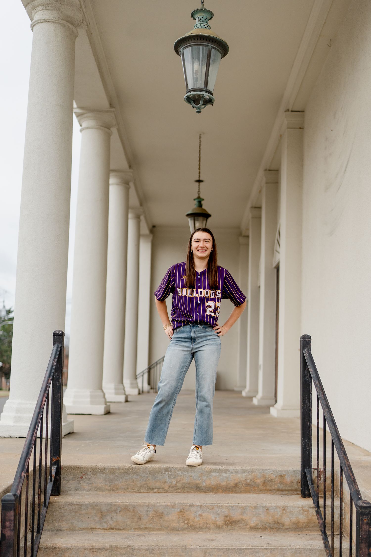 Portrait session under white columned architecture with vintage sports attire.