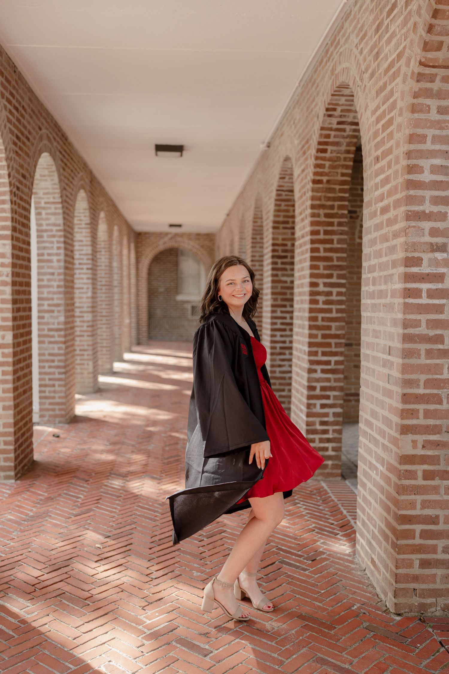 A series of four photos showing someone in a black jacket and red dress posing in a brick archway corridor.