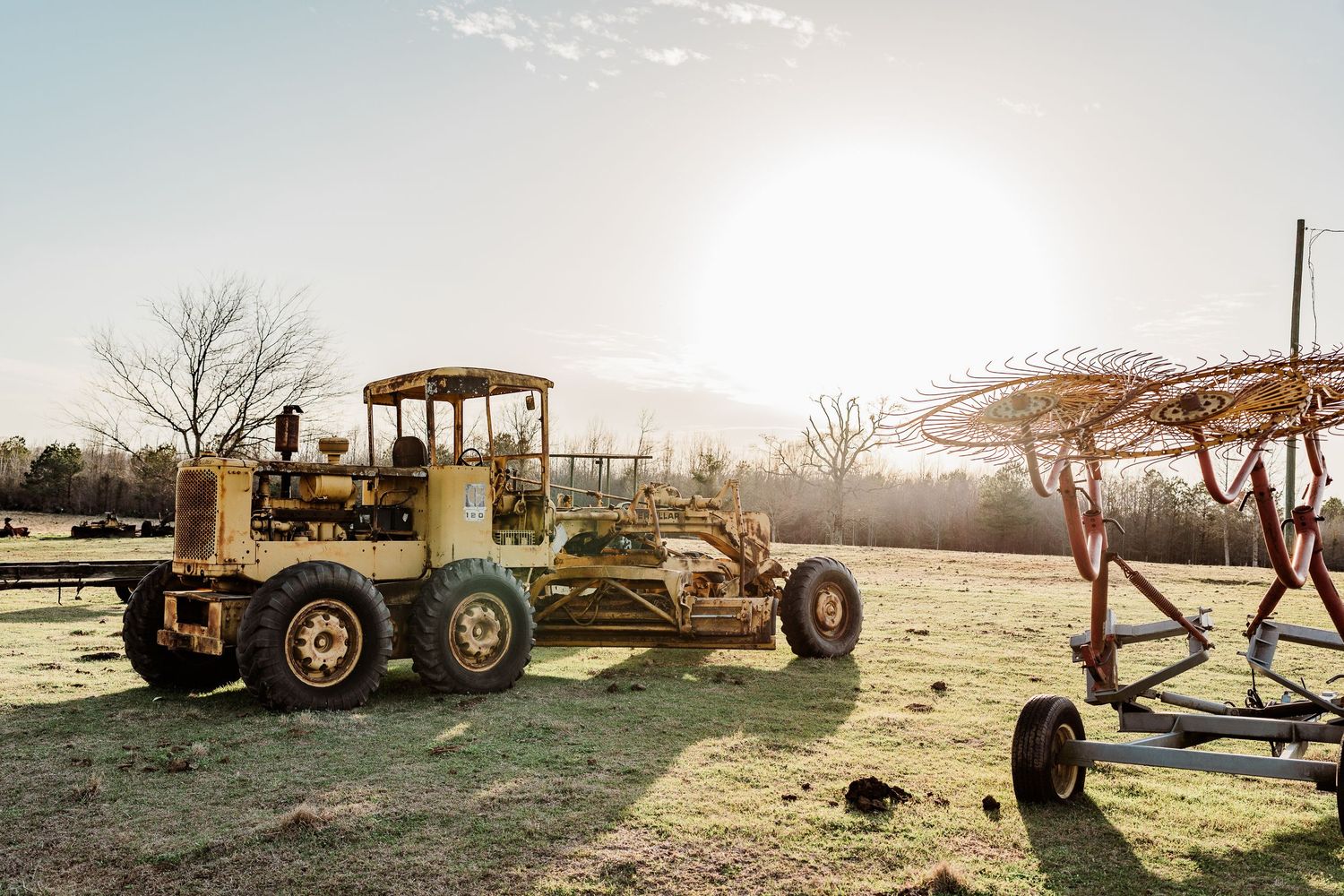 Farm equipment and machinery silhouetted against a bright sunset sky.