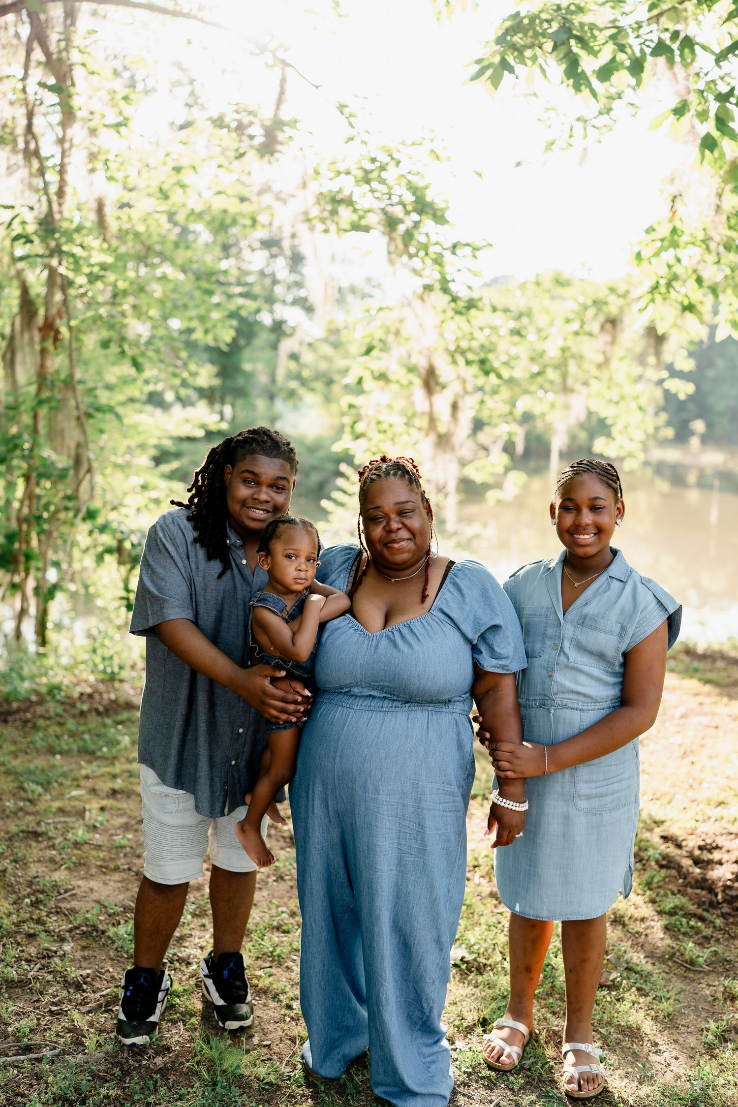 Group embraces while wearing matching blue outfits during an outdoor photo session near a lake.