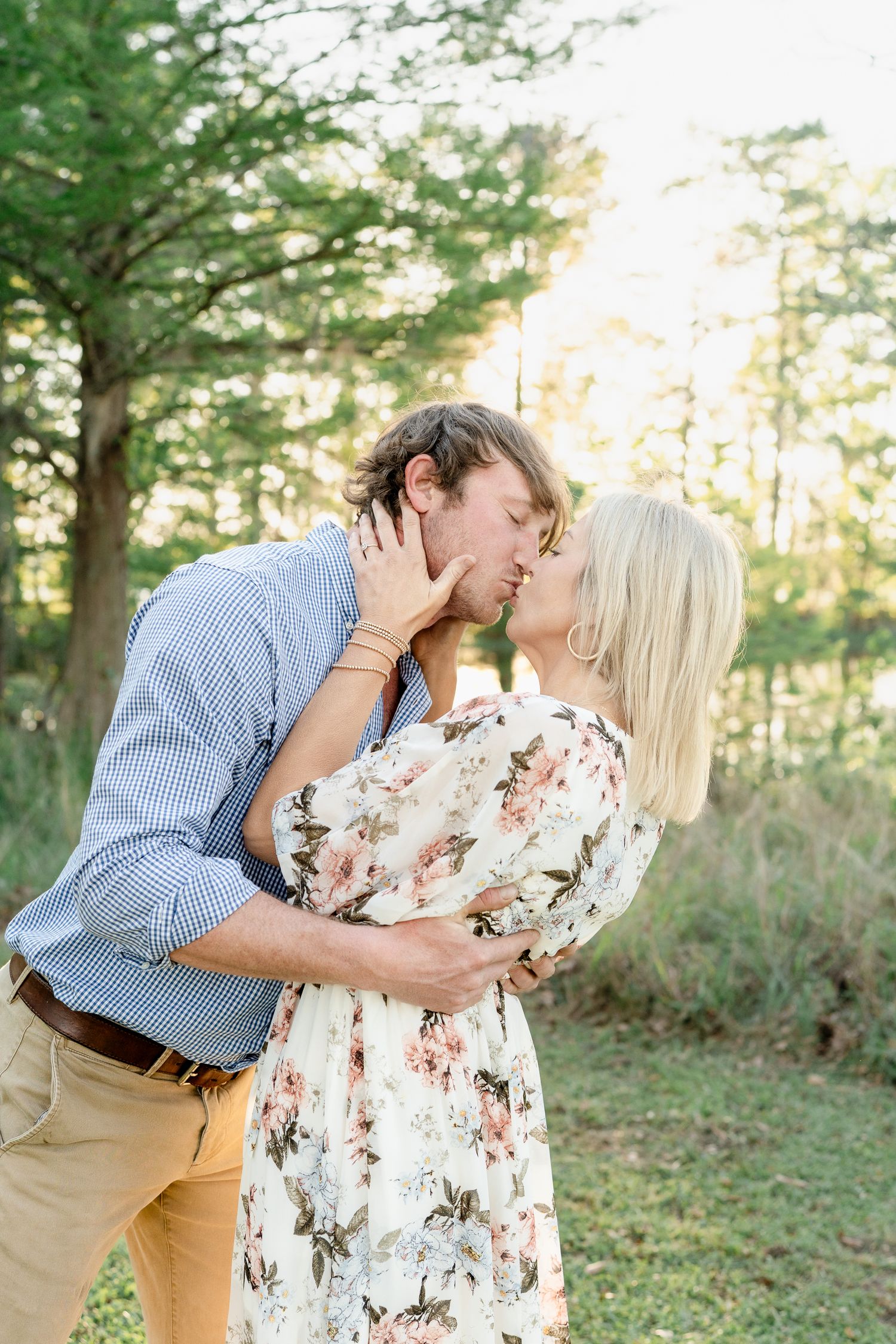 A tender embrace shared in a wooded setting with sunset light filtering through trees.