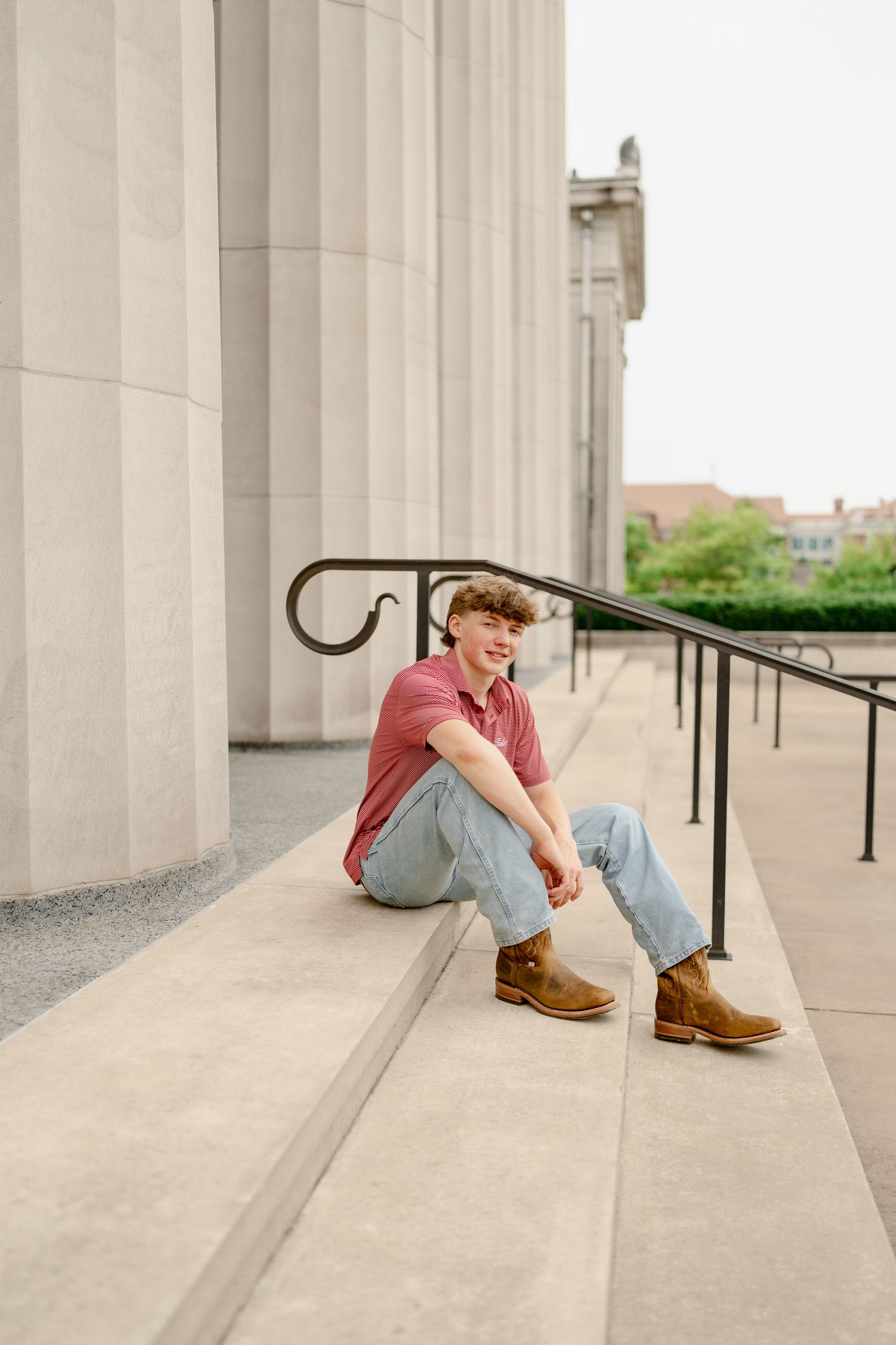 Artistic angle of someone seated on concrete steps between classical building columns.