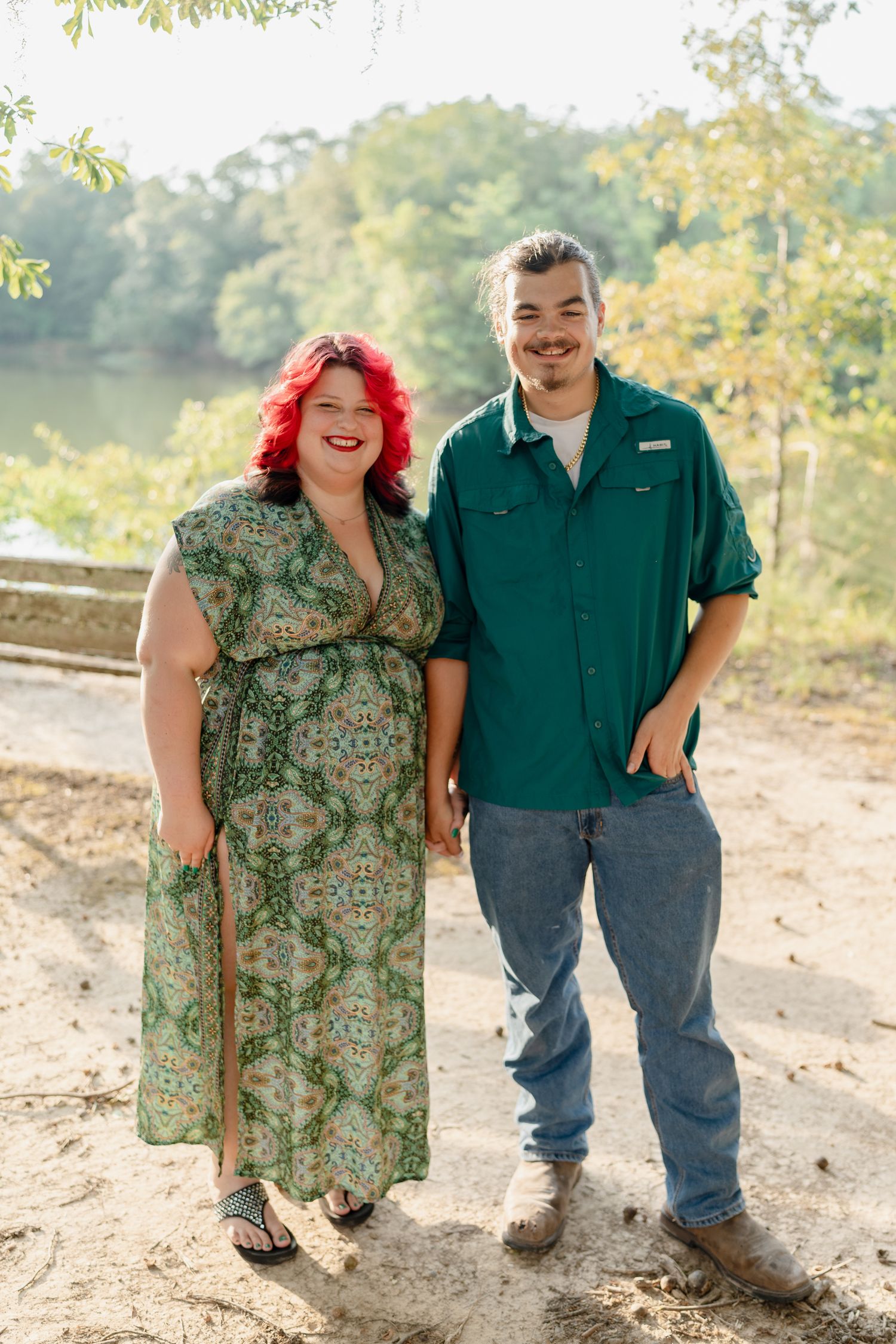 A couple in matching green outfits smiling and laughing together during an outdoor photoshoot.