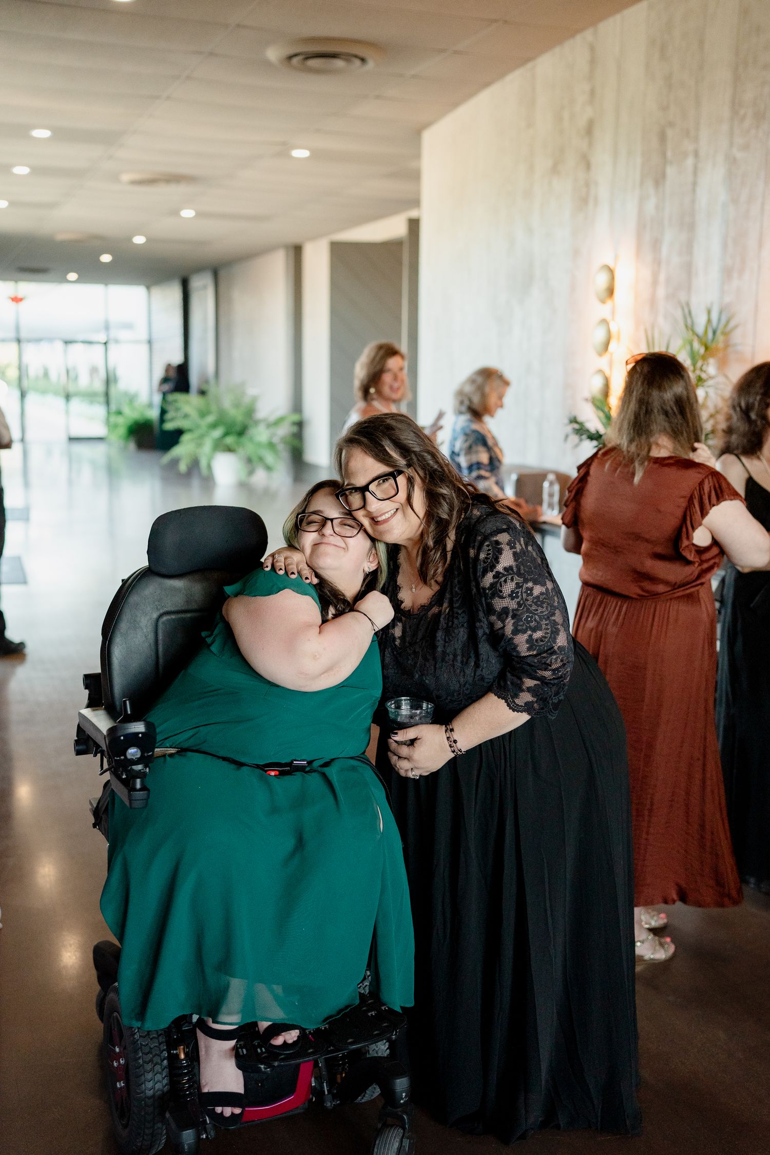 People dancing and embracing in a bright indoor venue with recessed lighting.