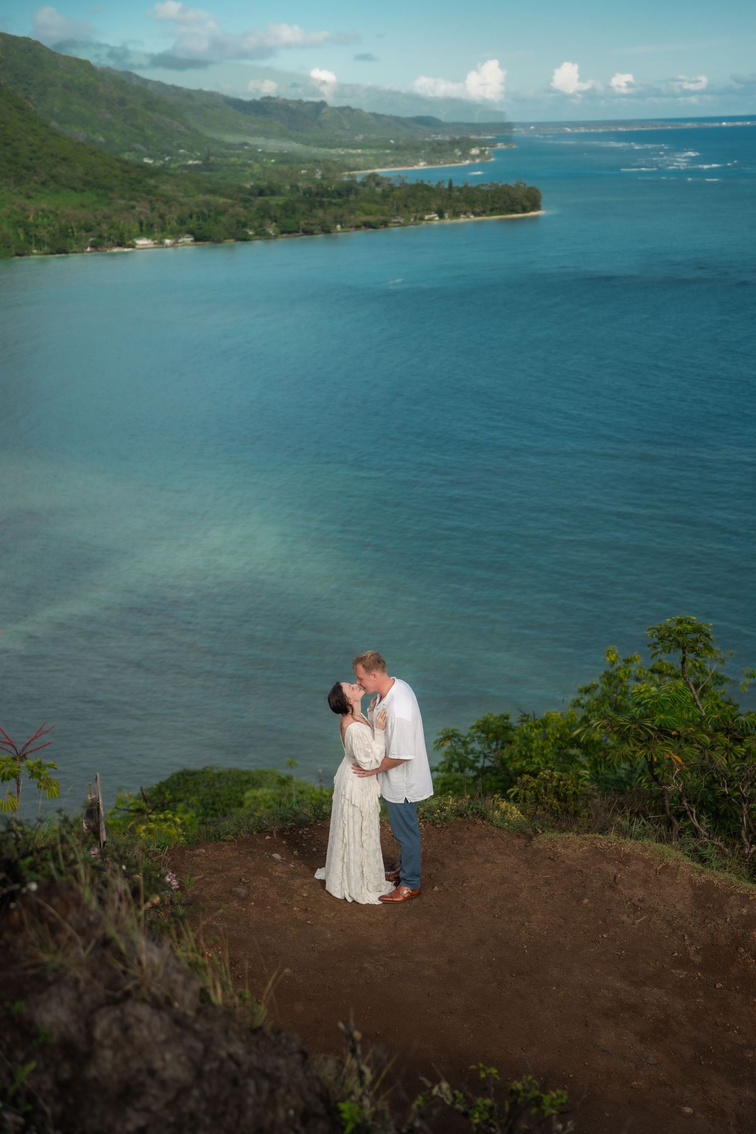 couple kissing on a mountain, ocean in back