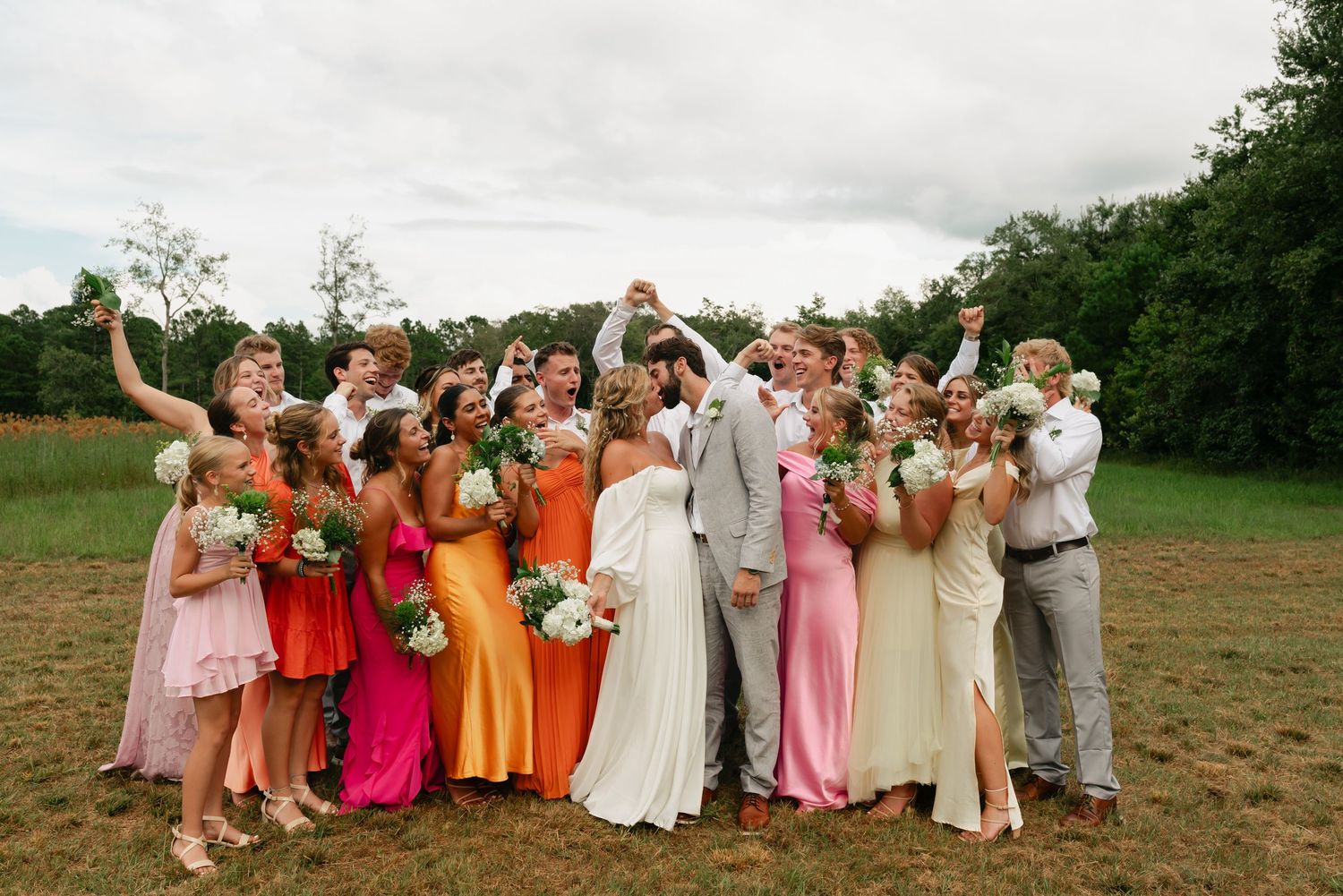 bride and groom  kissing while their bridal parties surround them cheering