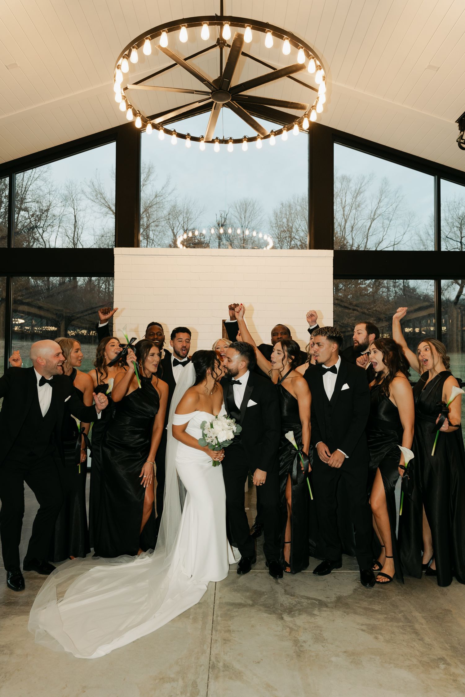 bride and groom  kissing while their bridal parties surround them cheering