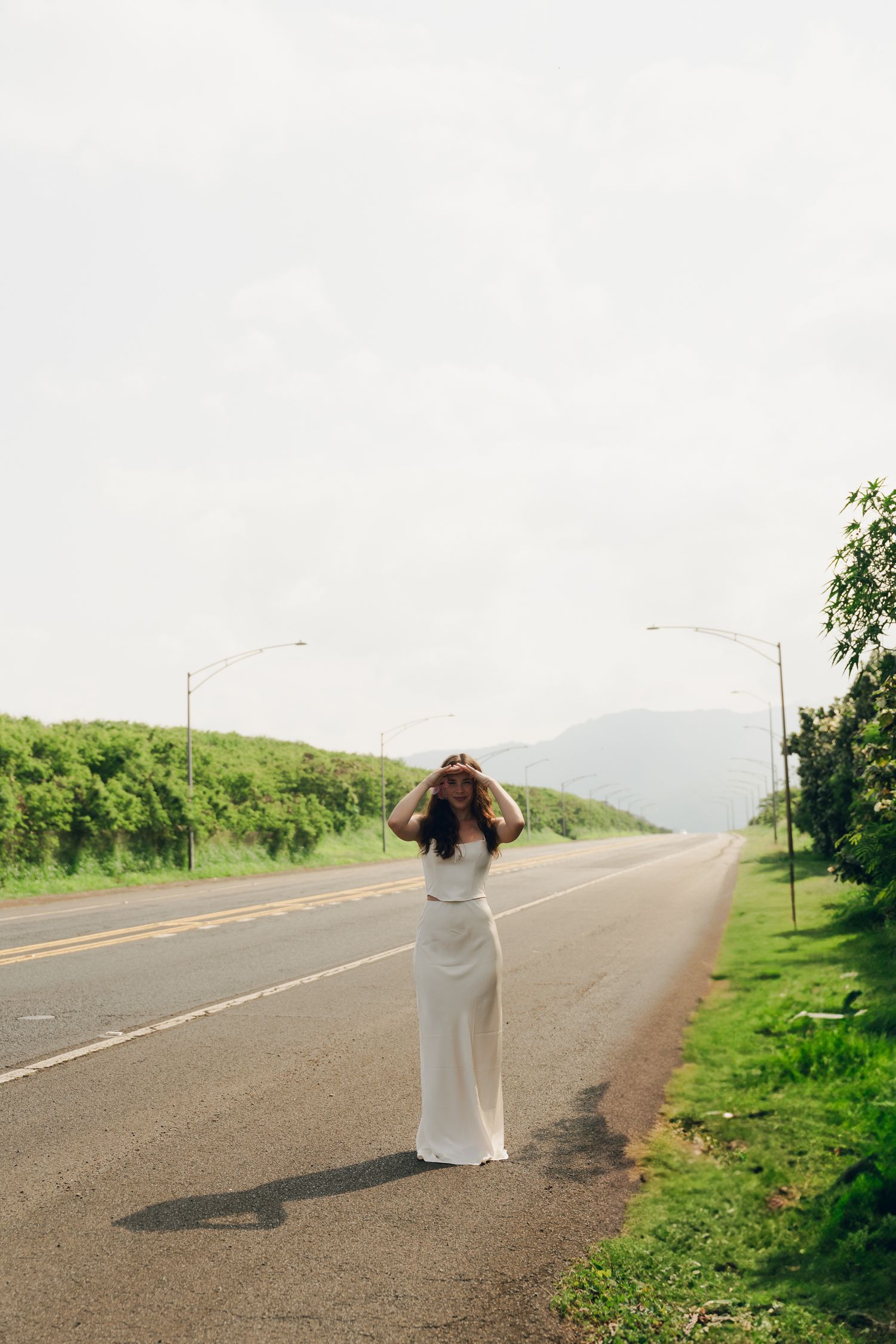 girl standing in a road with a mountain behind her