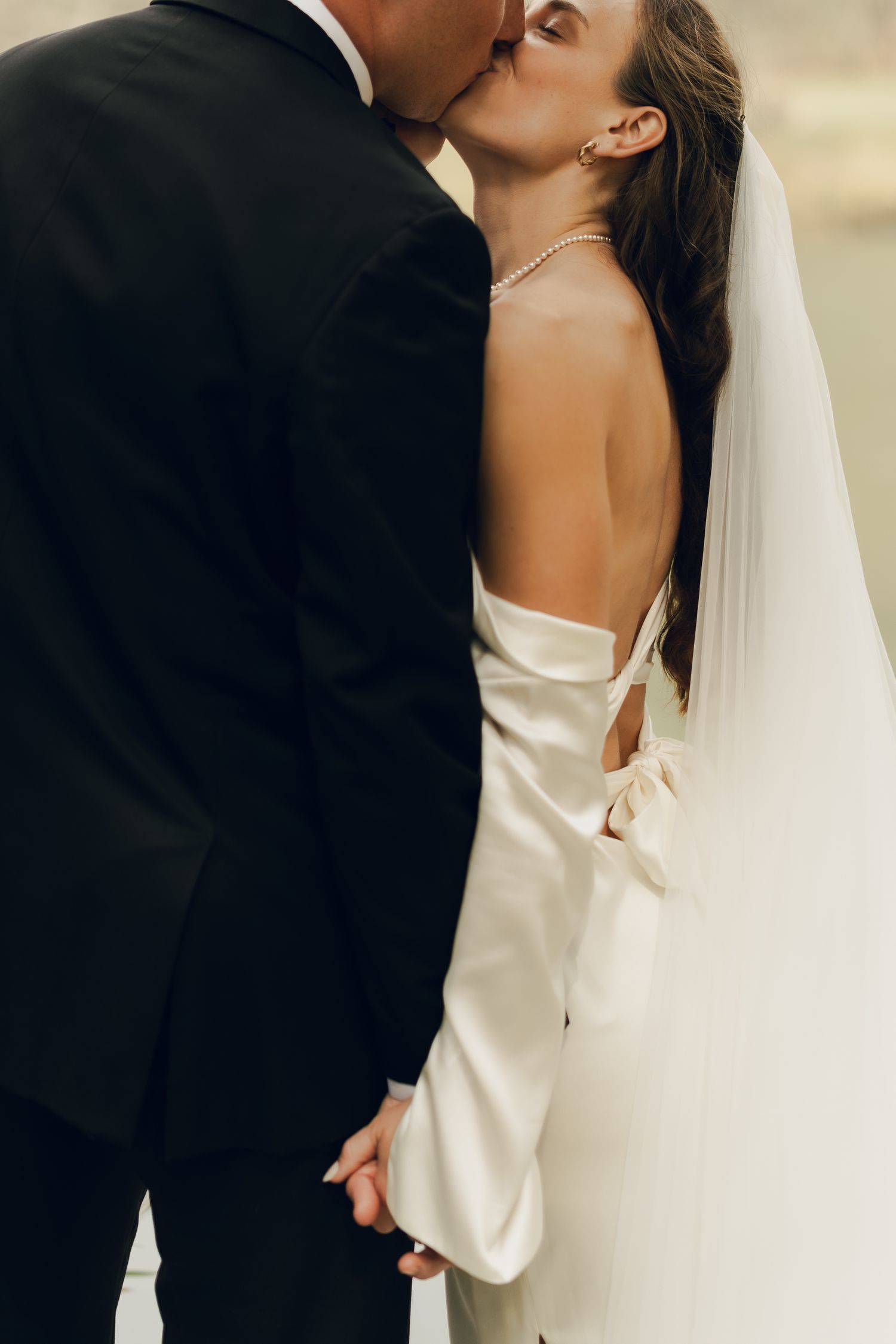 close up of wedding dress and grooms tux. holding hands