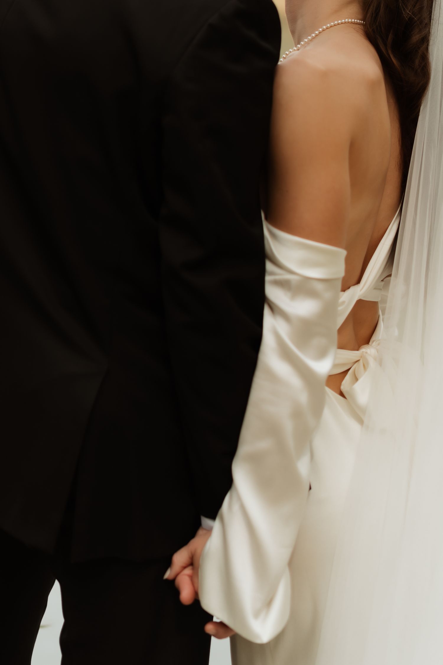close up of wedding dress and grooms tux. holding hands