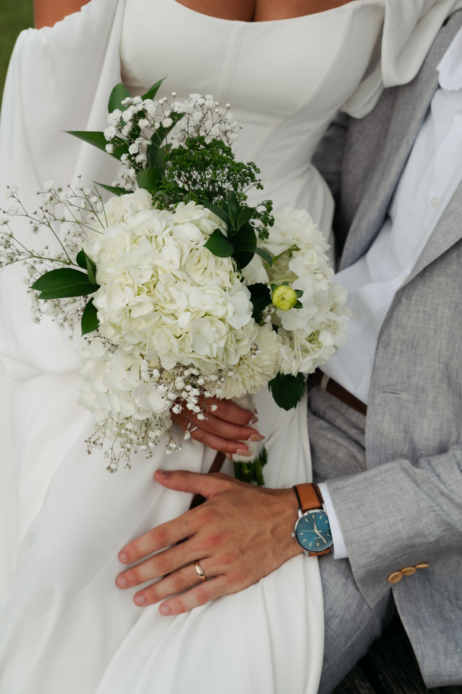 bride holding flowers while sitting on her husbands lap