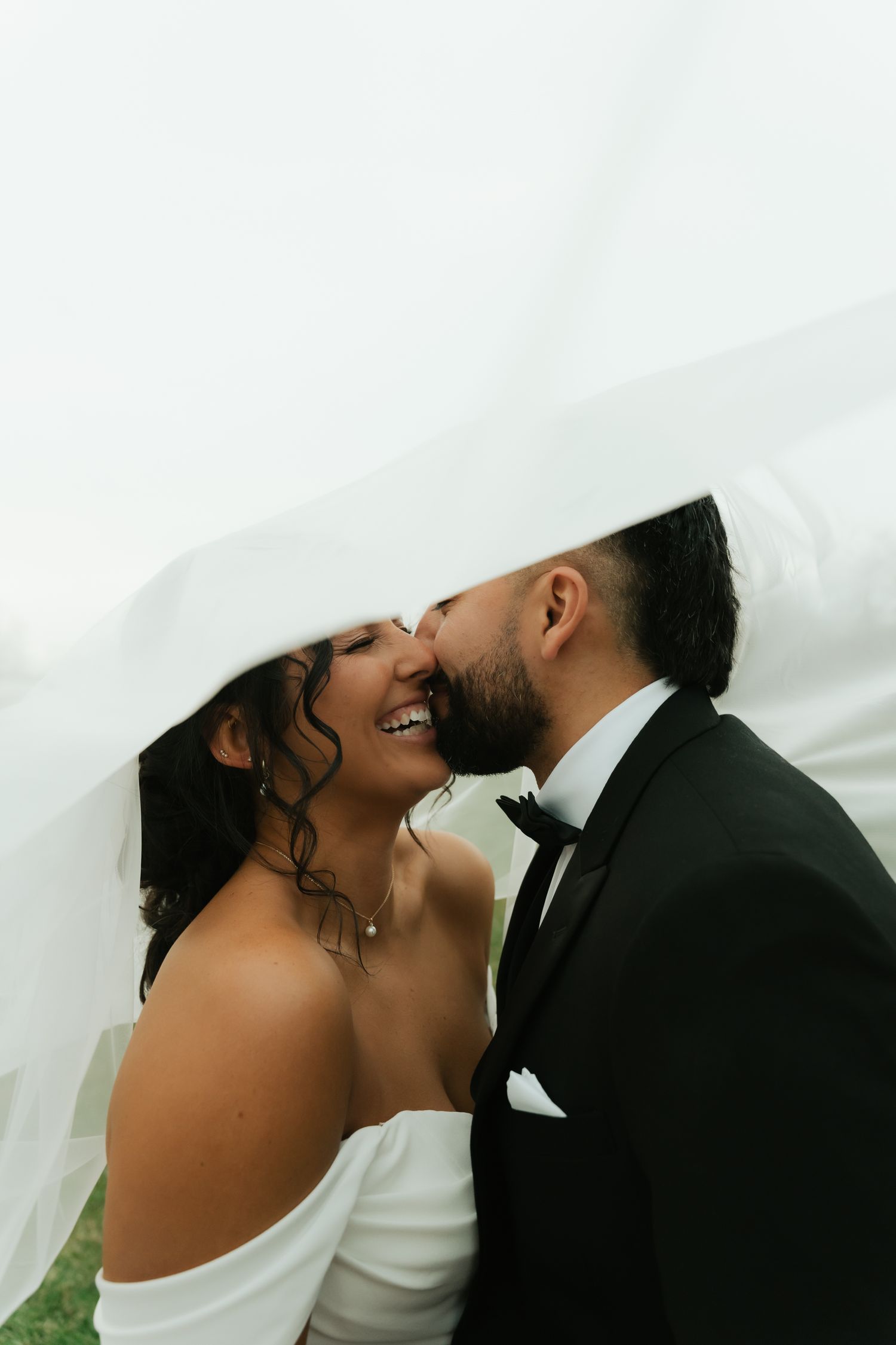 bride and groom kissing under veil