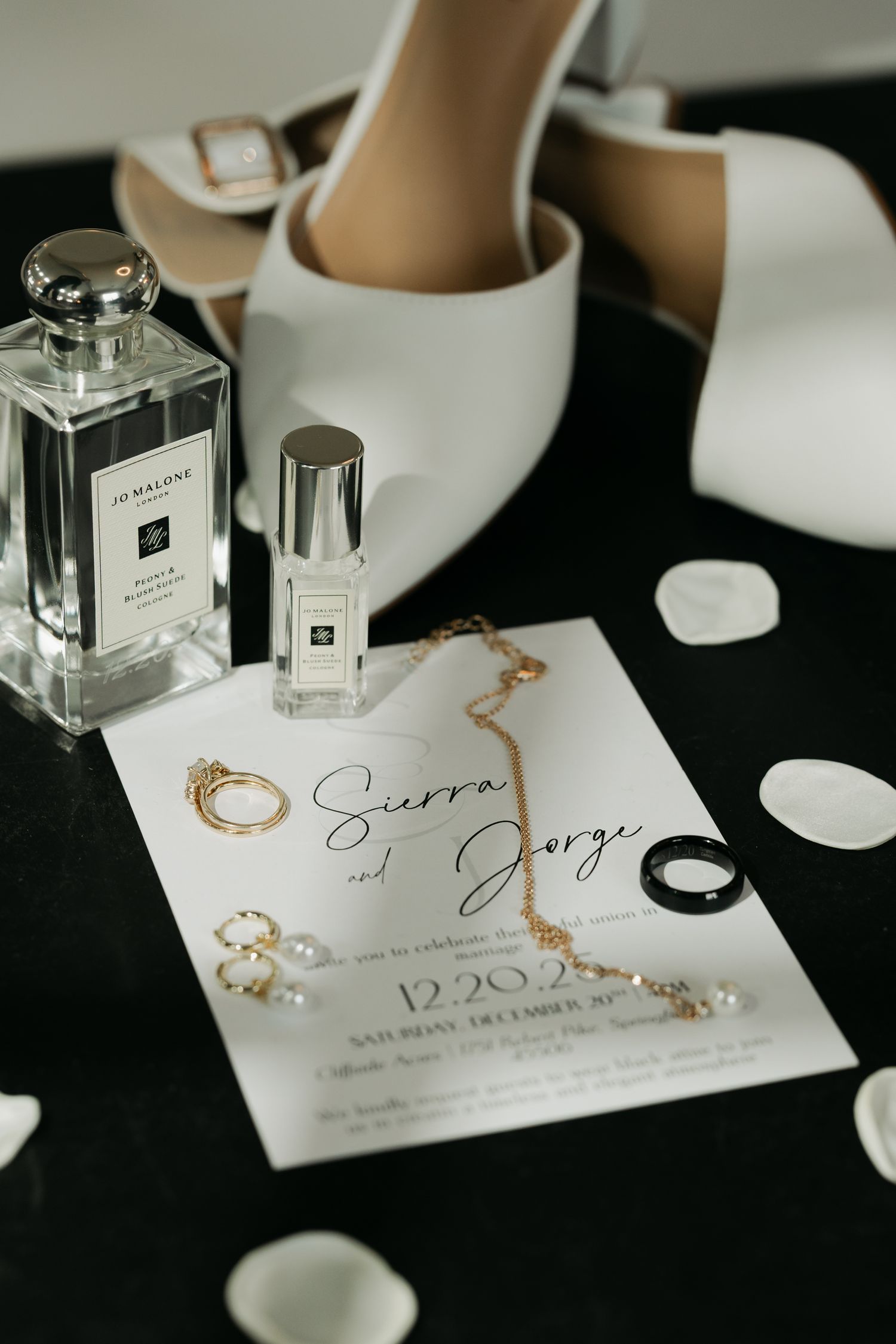 flatlay, with invitation, shoes, petals, rings, perfume.