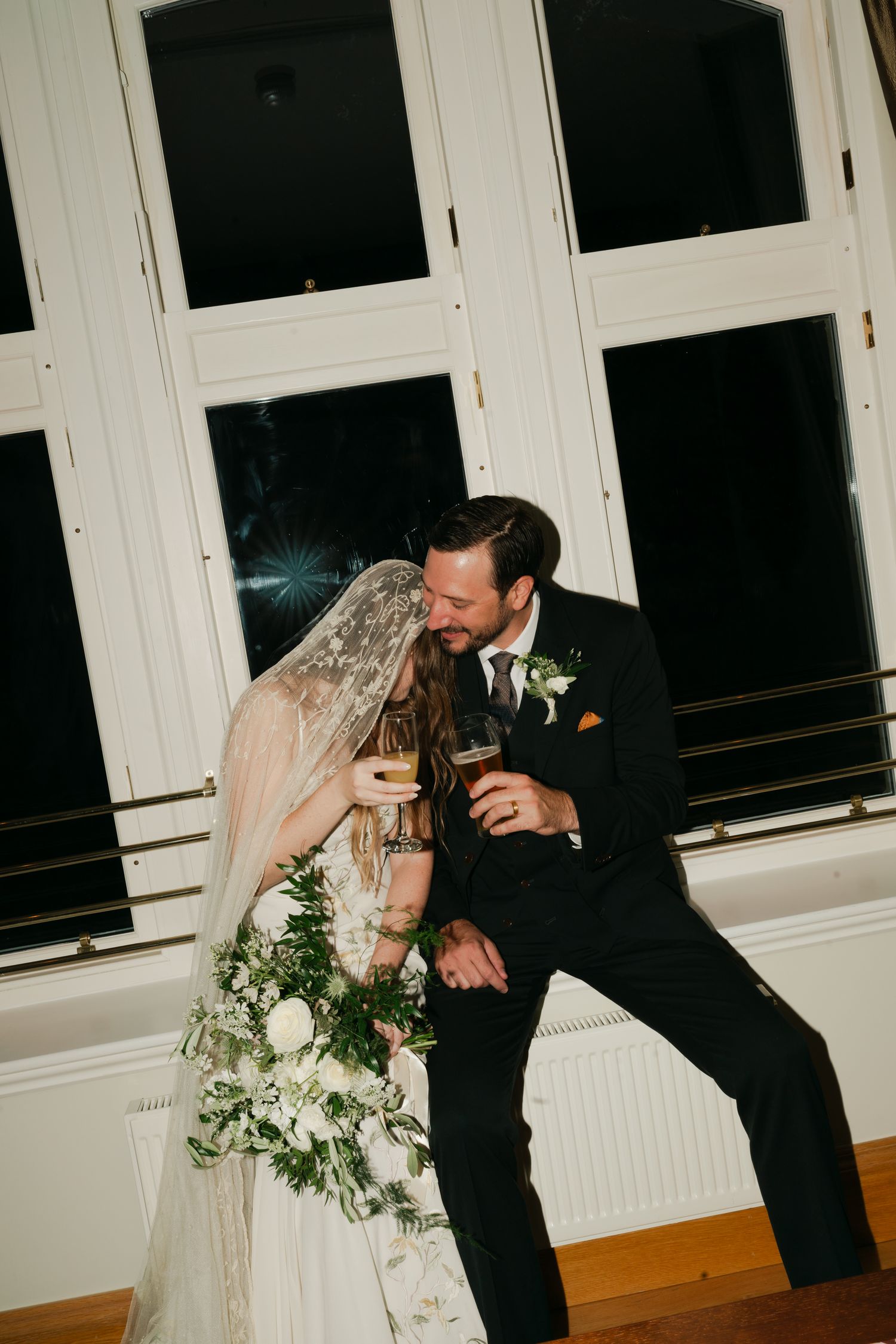 couple sitting on window seal, drinking wine