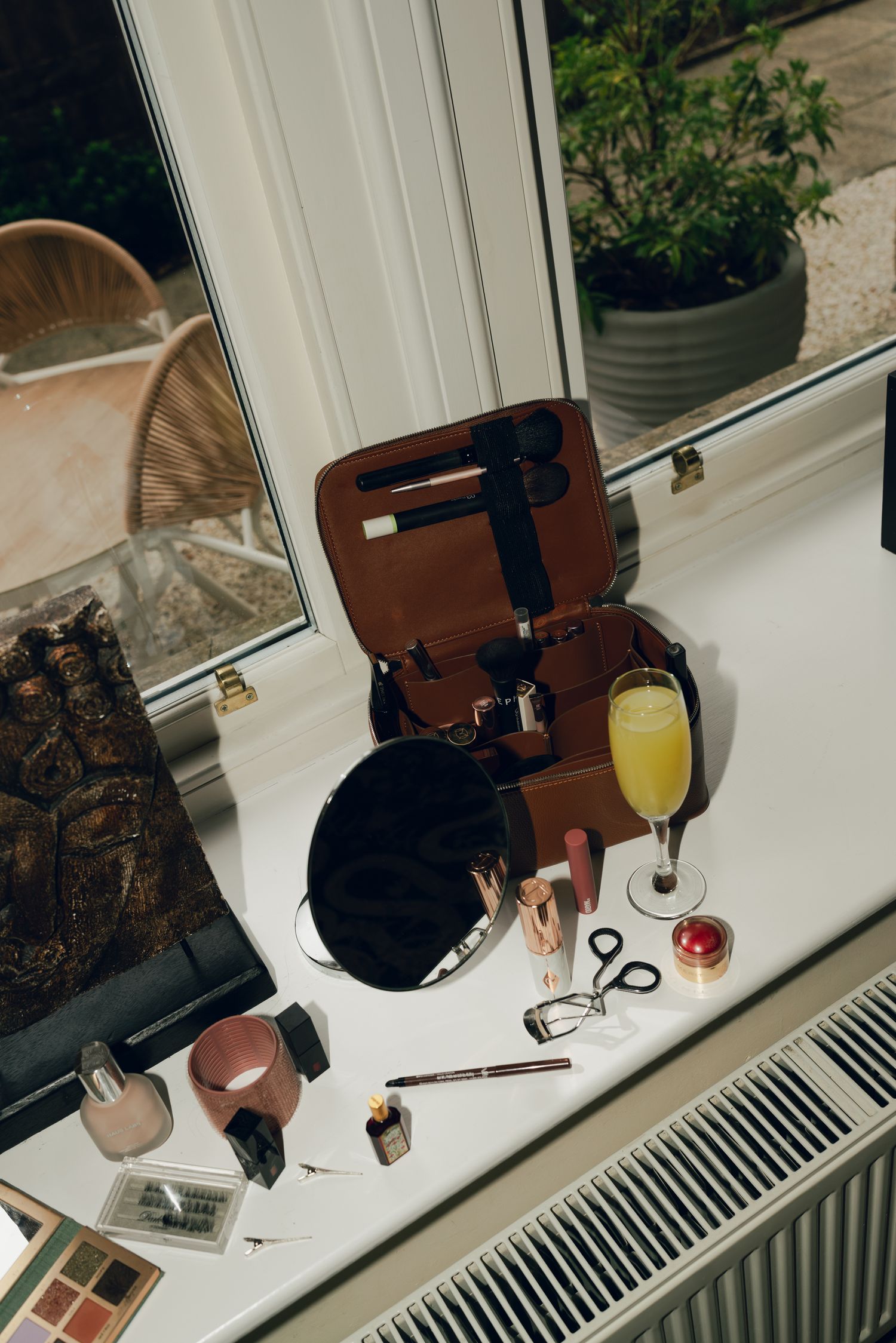 makeup spread out on a window seal with a mimosa