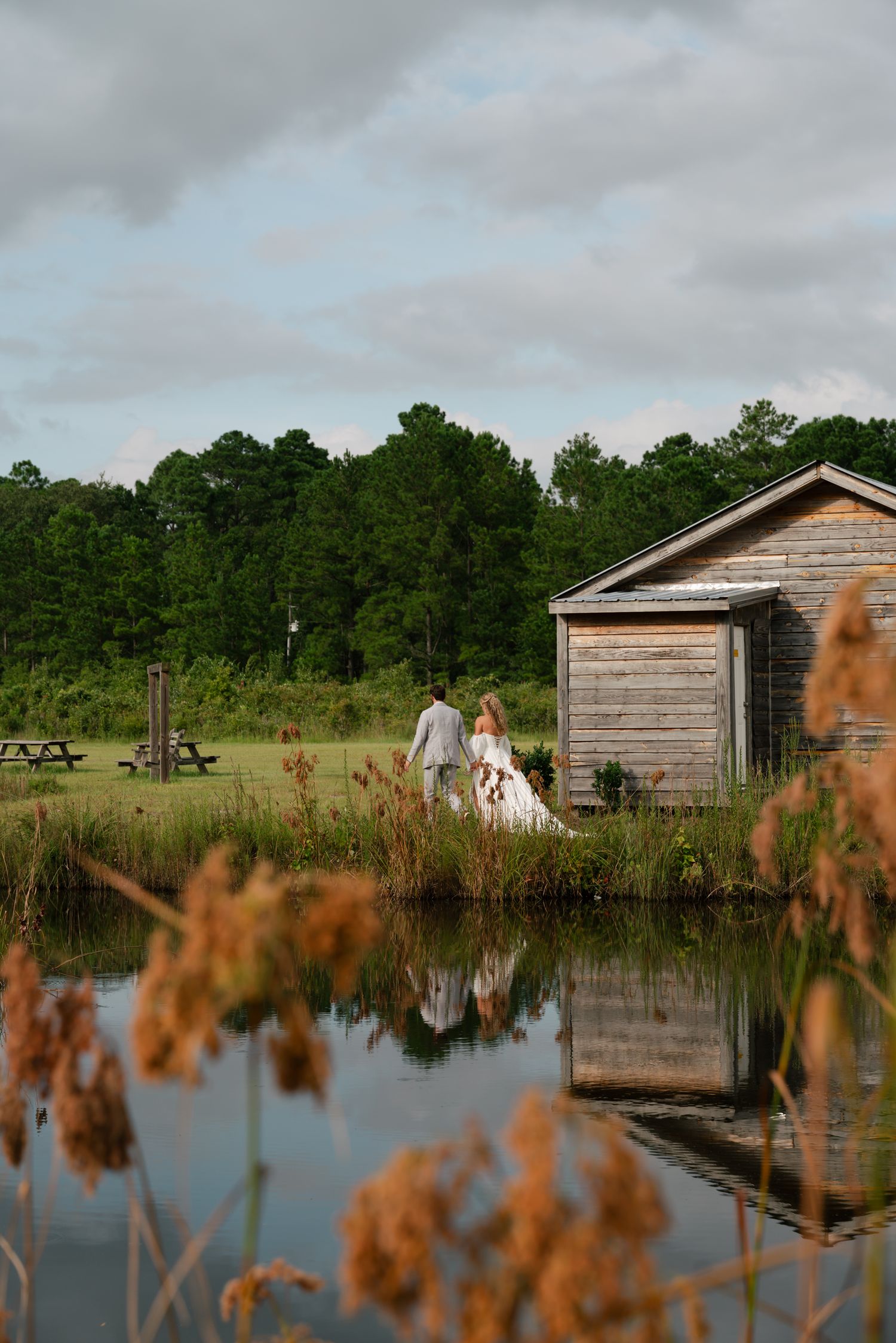 bride and groom walking with a pond in front